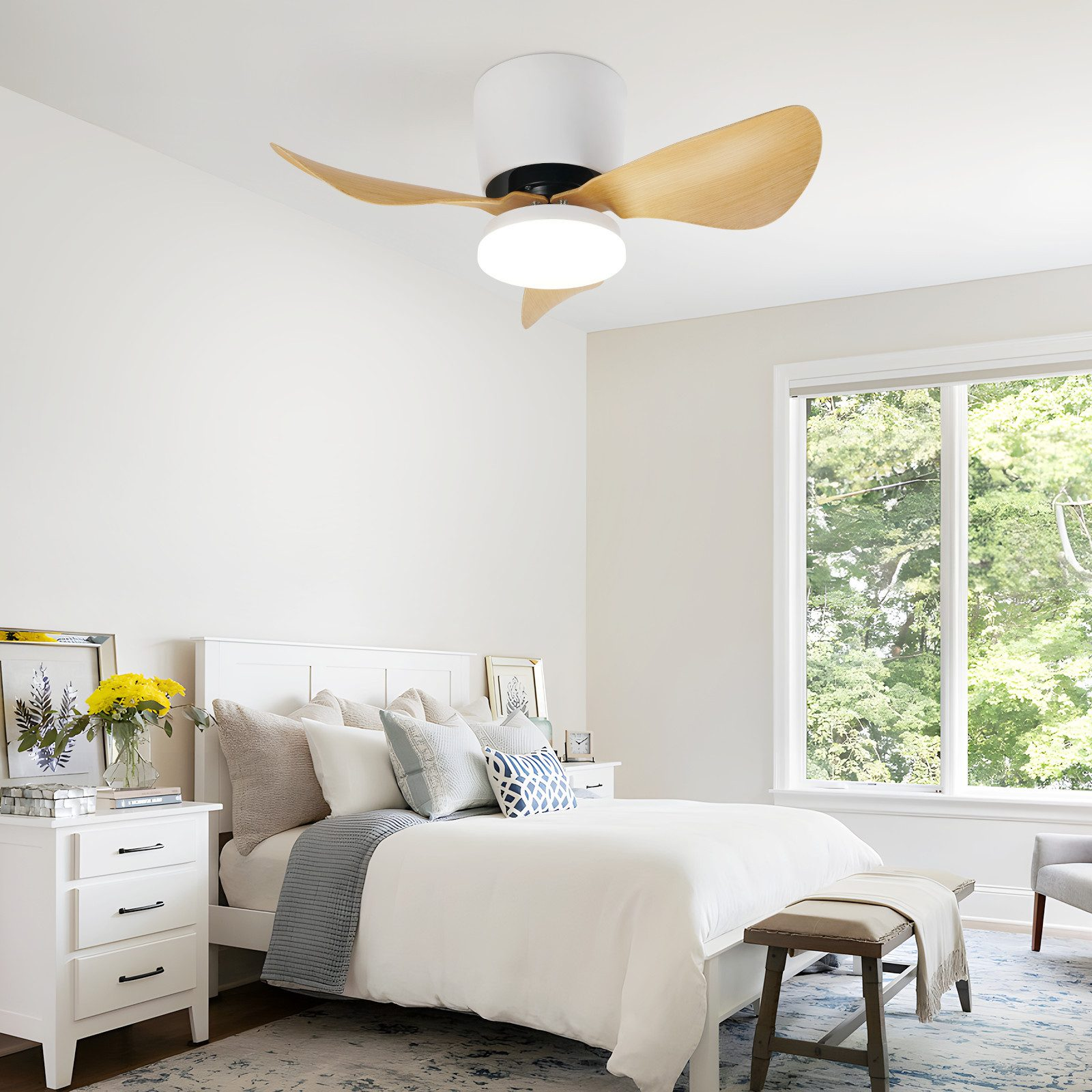 Camera da letto con mobili bianchi, ventilatore a soffitto e ampia finestra con vista sugli alberi.