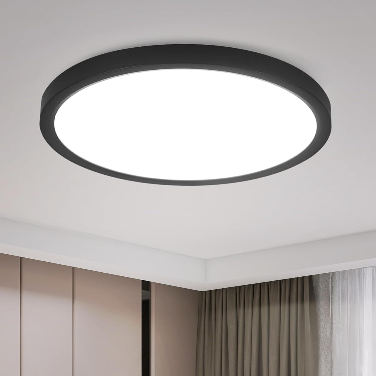 Una luce da soffitto rotonda e nera illumina una stanza. Sullo sfondo si vedono pareti beige e tende marroni.