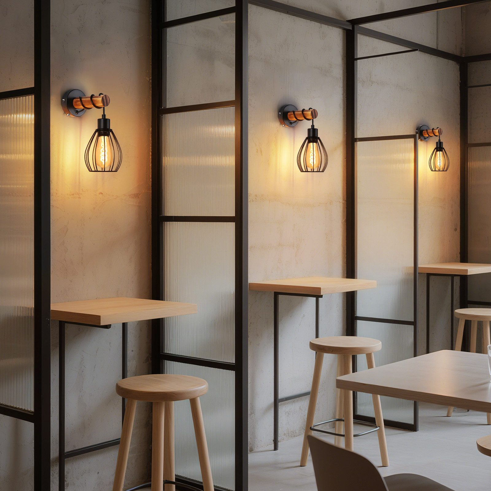 Interni di un ristorante con tavoli e sgabelli in legno. Sono visibili divisori in vetro con struttura metallica e luci decorative.