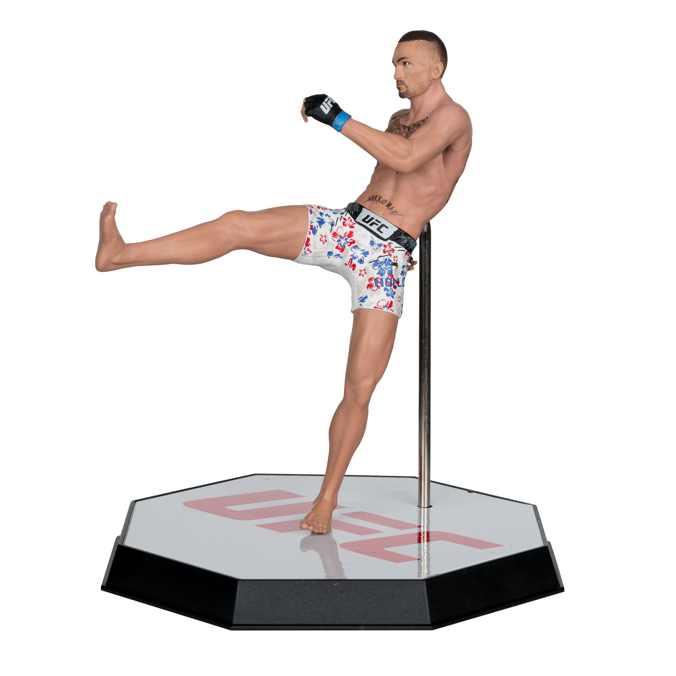Eine UFC-Figur eines Mannes in Shorts, der tritt. Er steht auf einem Ständer mit dem UFC-Logo. Weißer Hintergrund.