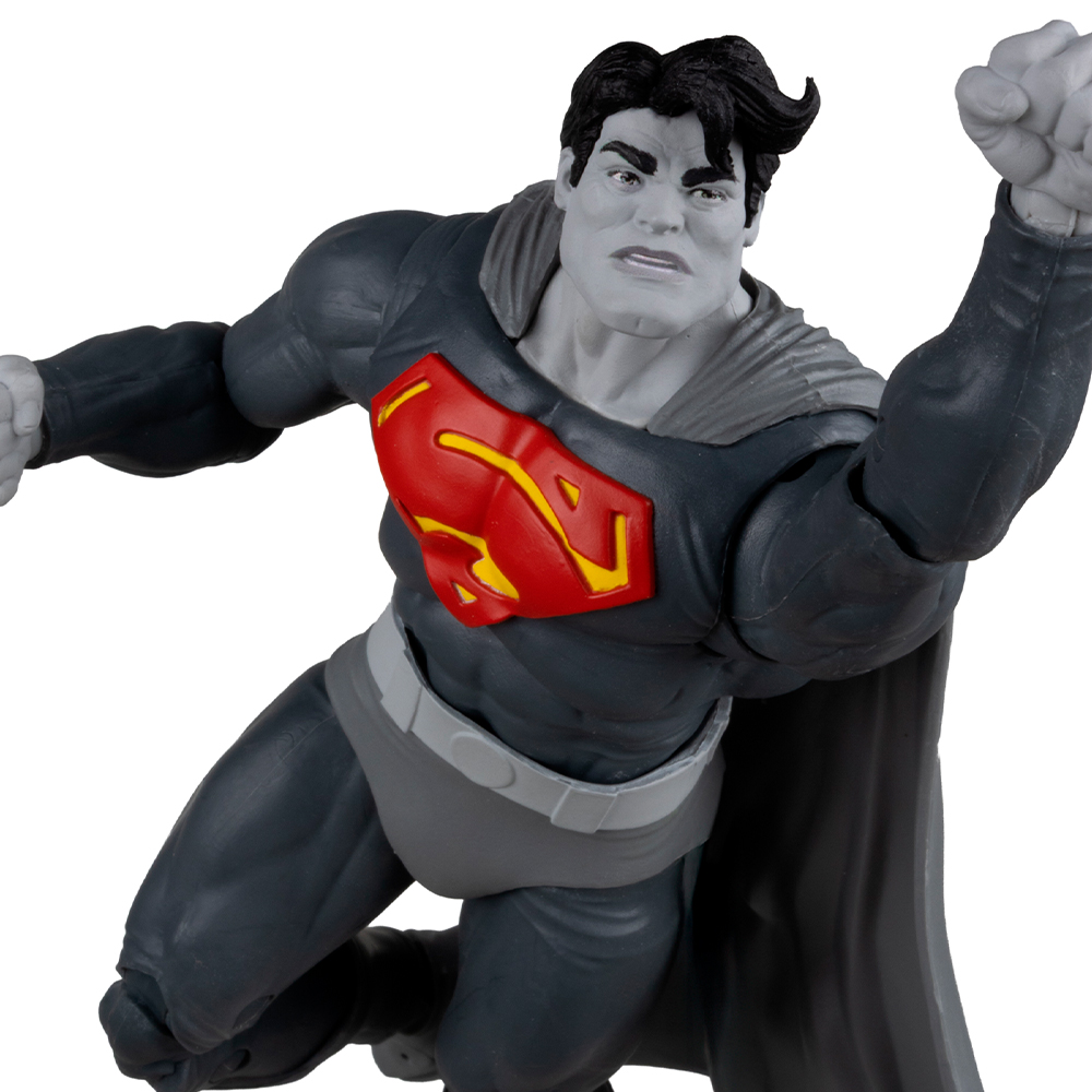 Action figure di Superman a mezz'aria, tuta grigia e nera con emblema rosso e giallo. Capelli neri, pelle grigia, mantello.