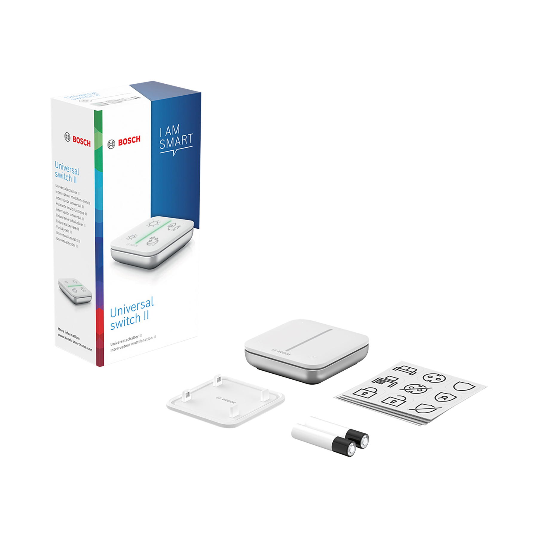Box mit 'Universal Switch II', Fernbedienung, Basis, Abdeckung, Batterien und Aufklebern. Alle Artikel sind weiß und silber.