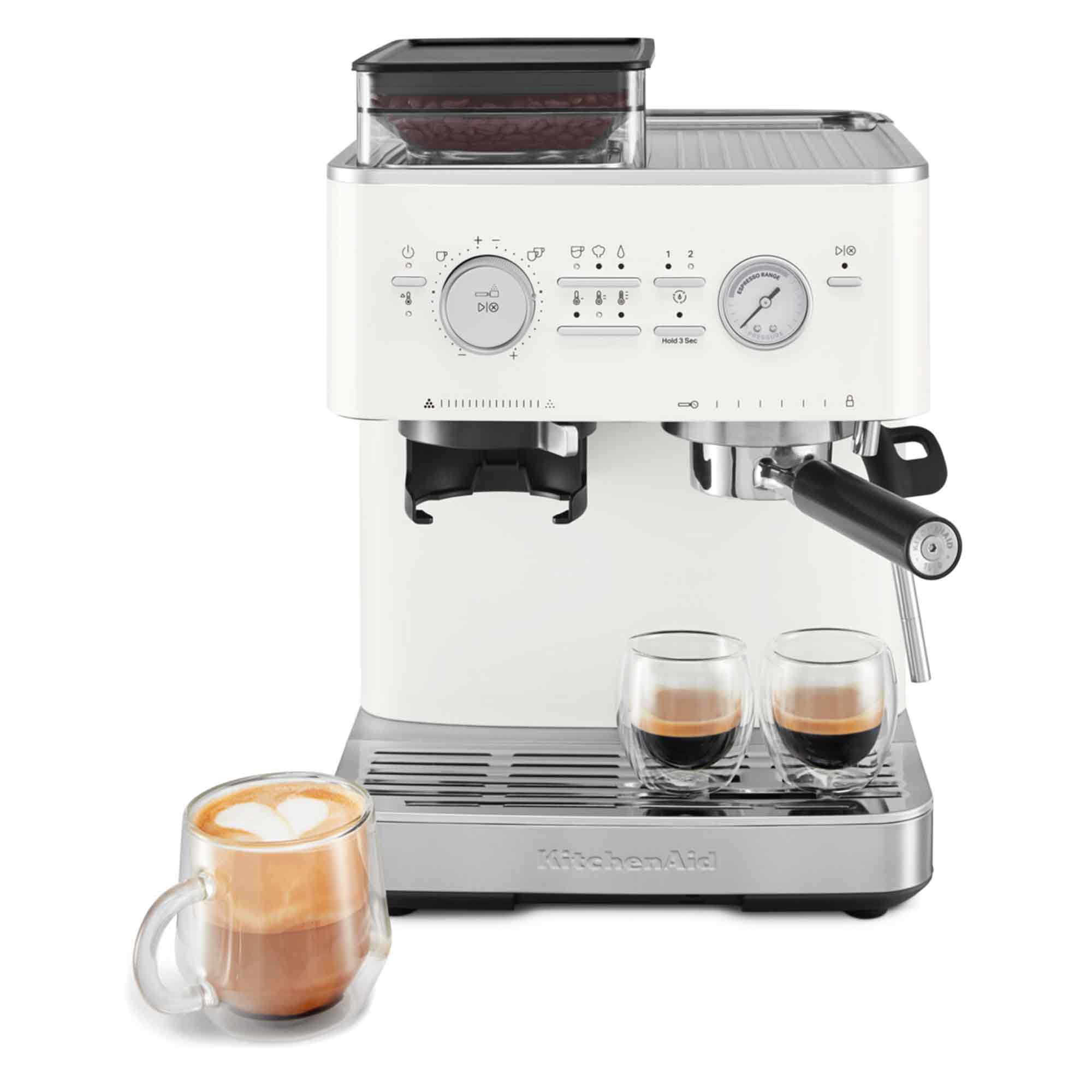 Weiße KitchenAid Espressomaschine mit Kaffeebohnen, zwei Espresso-Shots und einem Latte.