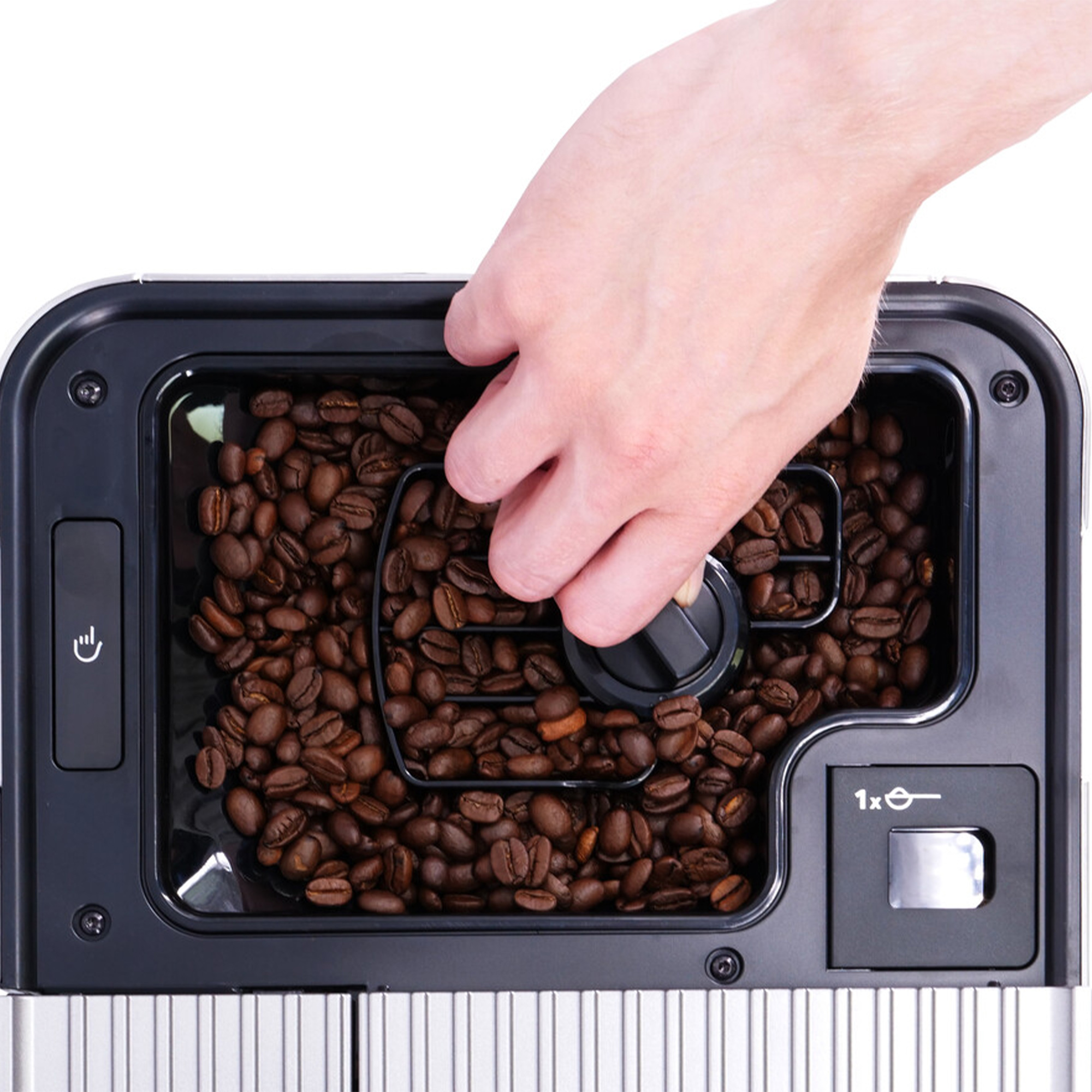 Een hand stelt een zwarte draaiknop af op een koffiezetapparaat gevuld met bruine koffiebonen. De machine heeft een zwart frame.