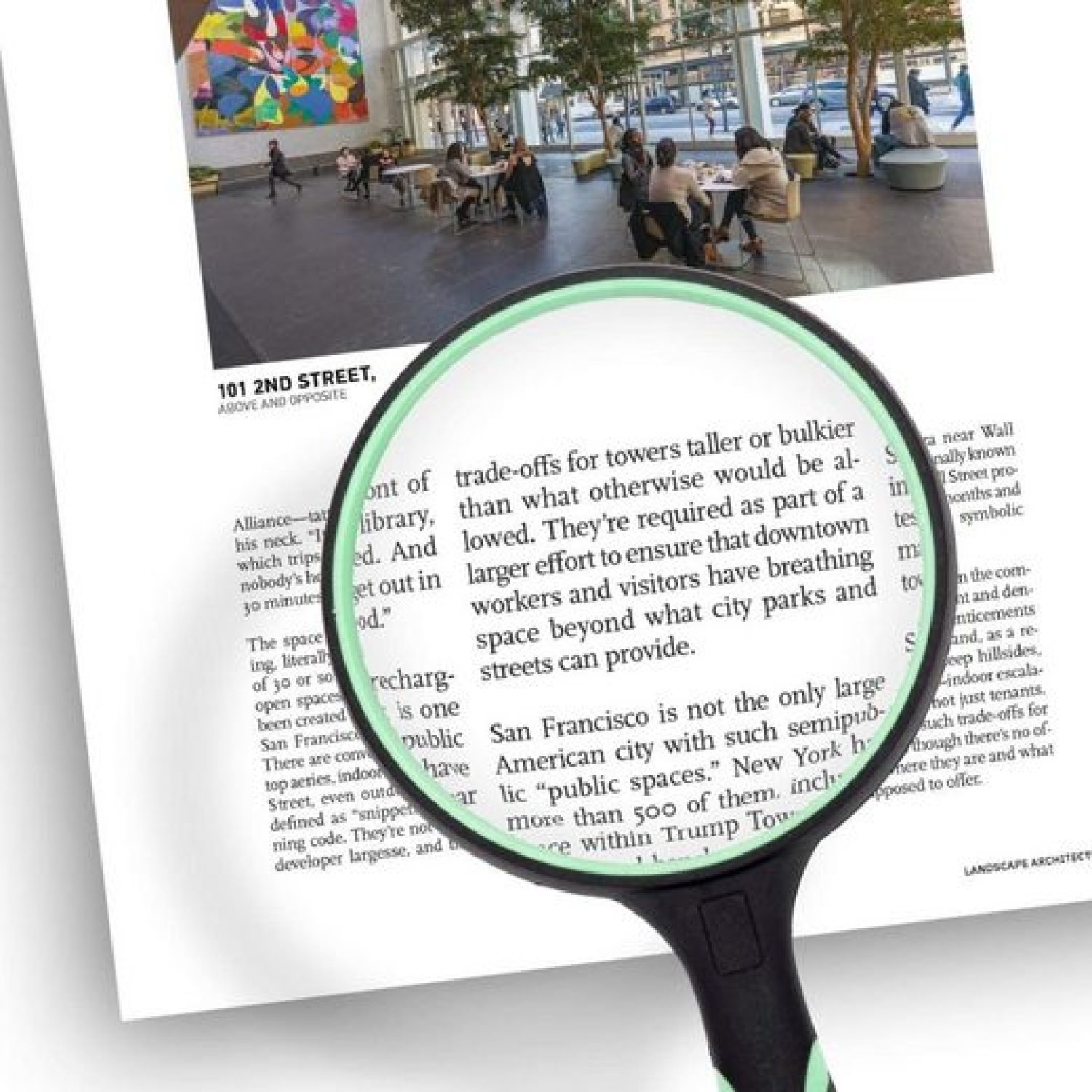 Eine Lupe über einem Text über Stadtplanung. Im Hintergrund sitzen Menschen an Tischen unter einem farbenfrohen Gemälde.