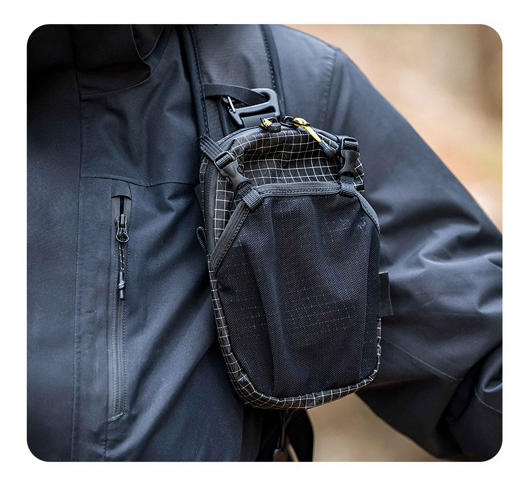 Eine Person trägt eine schwarze Jacke mit einer kleinen Rucksacktasche vorne befestigt.