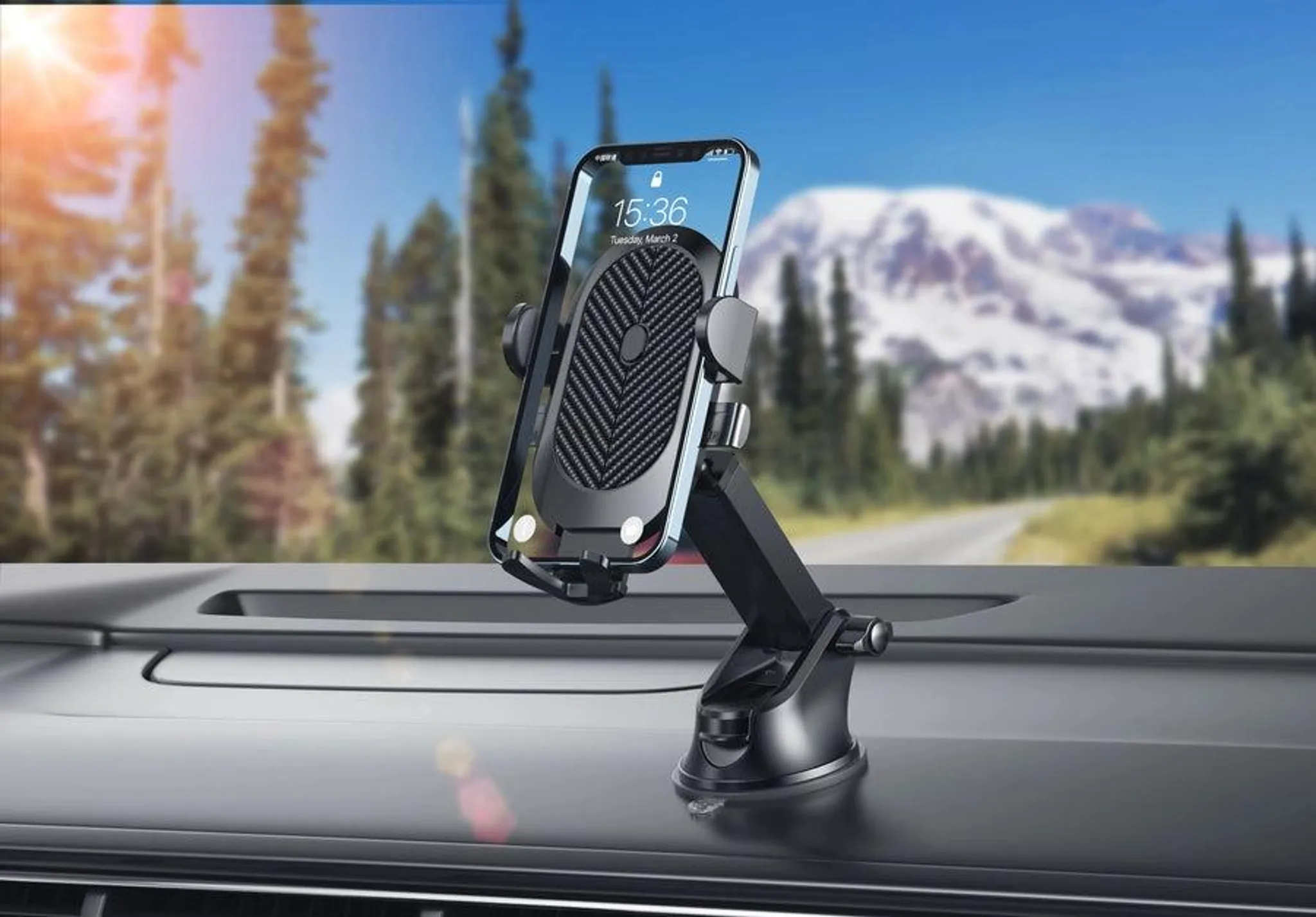 Ein Telefon ist auf dem Armaturenbrett eines Autos montiert. Der Hintergrund zeigt Bäume, eine Straße und einen Berg.