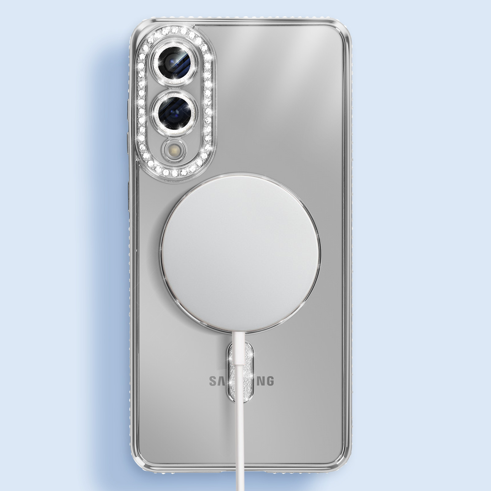 Una custodia trasparente per telefono con un anello per fotocamera incrostato di diamanti e un caricatore circolare bianco. È collegato un cavo bianco.