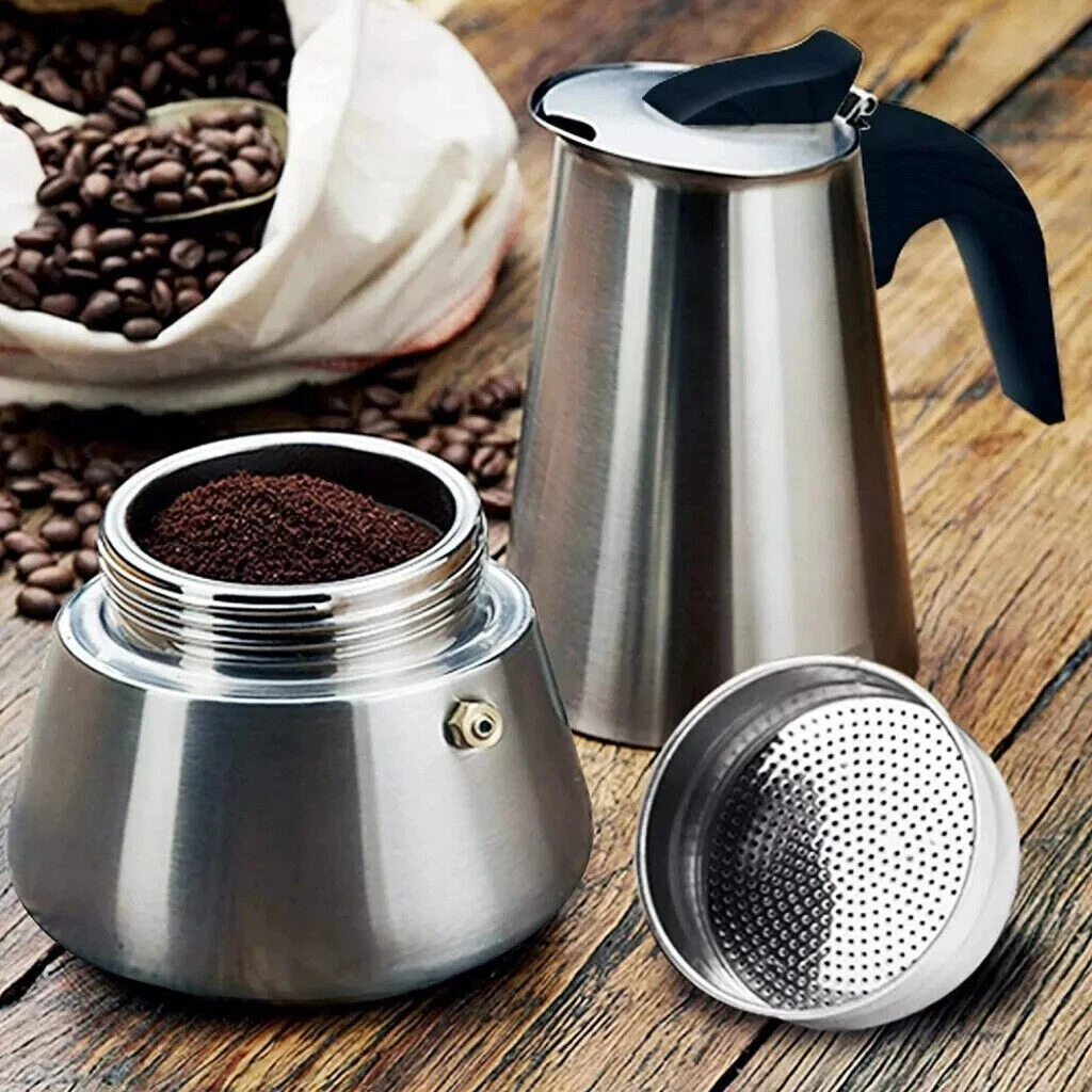 Kaffeezubereitungsgeräte: eine Espressokanne, eine Tüte Bohnen und gemahlener Kaffee. Die Szene spielt auf einer Holzoberfläche.