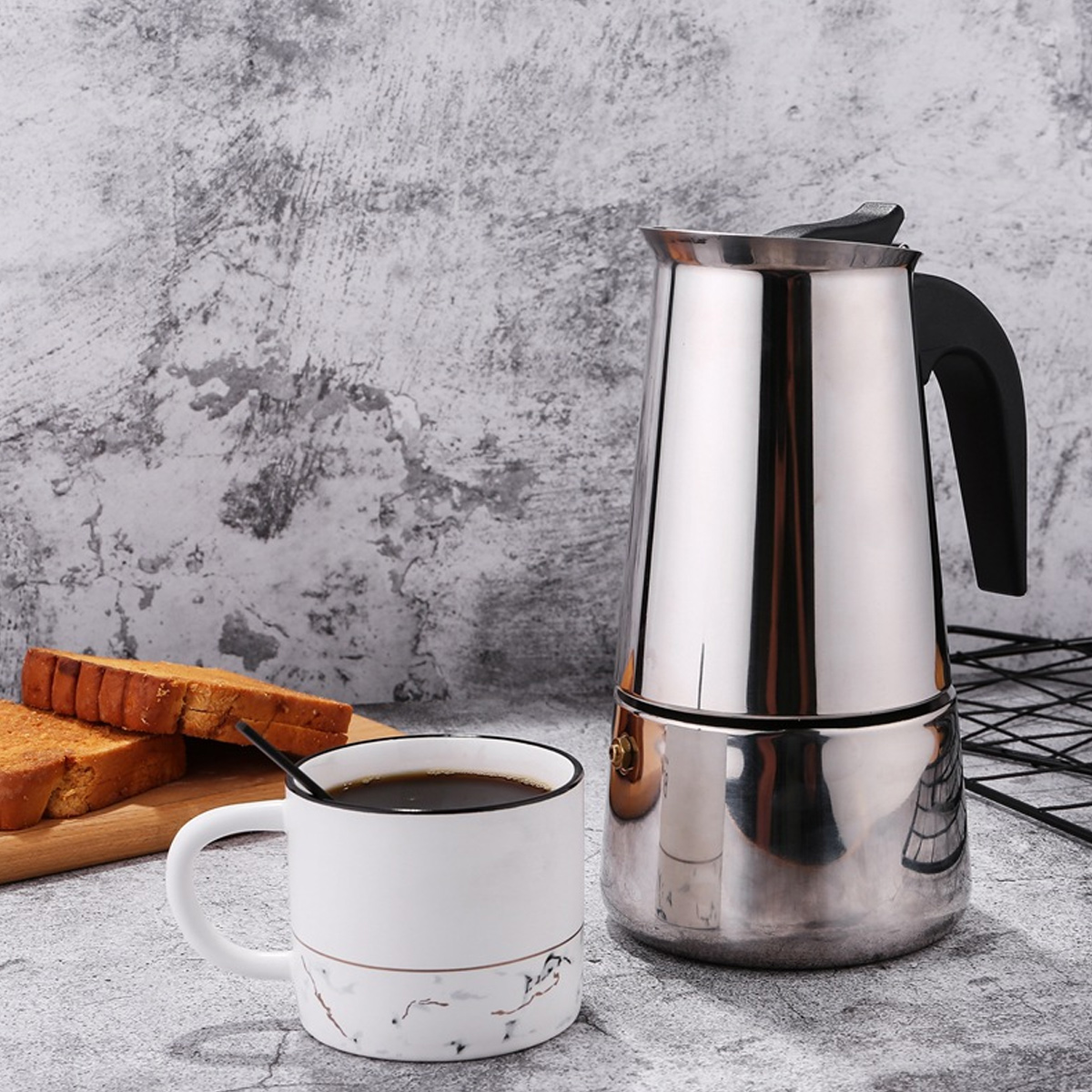Ein Kaffee-Setup mit einer weißen Tasse, einer Kaffeemaschine und Toastscheiben auf einem Holzbrett. Der Hintergrund ist eine graue Wand.