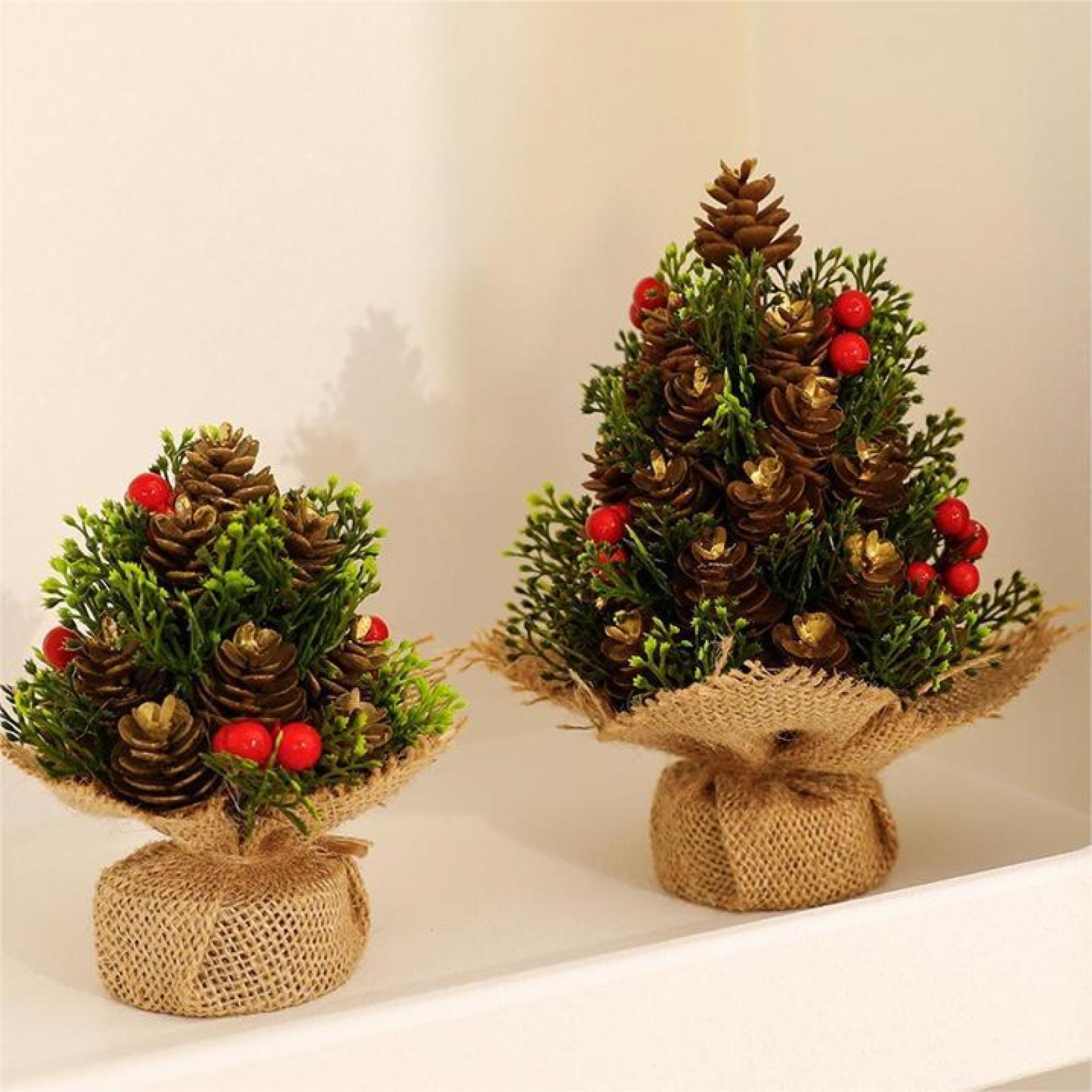 Zwei kleine Weihnachtsbäume mit Tannenzapfen und roten Beeren stehen auf einem weißen Regal, umwickelt mit Jute.