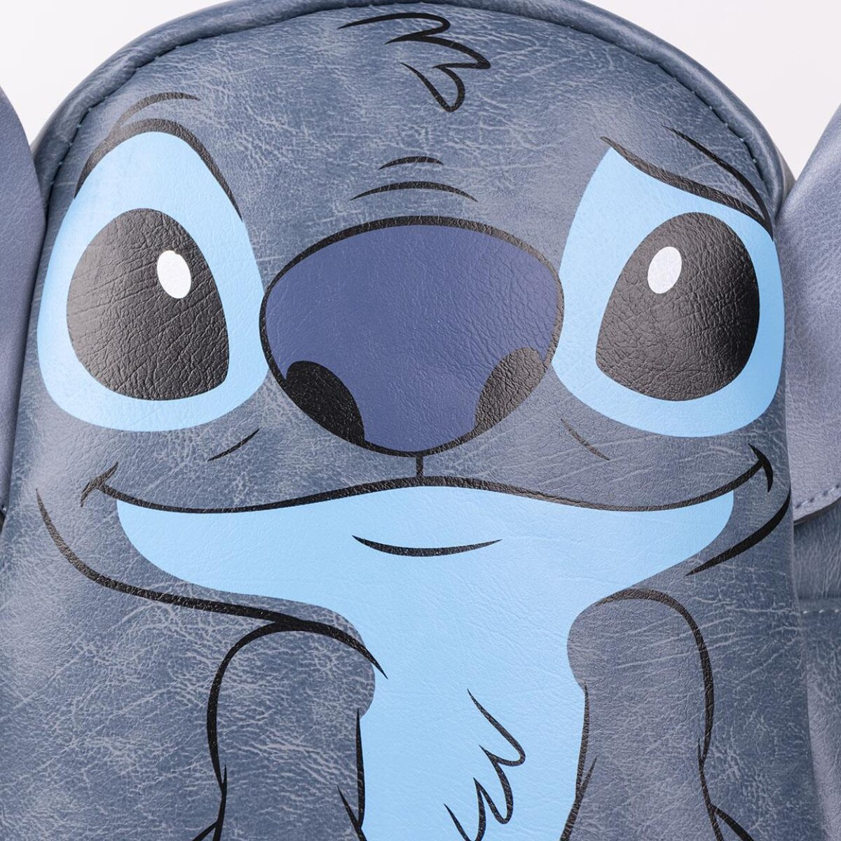 Primer plano de la cara del personaje Stitch. Predominan los tonos azules y grises, con ojos grandes, nariz oscura y boca sonriente.