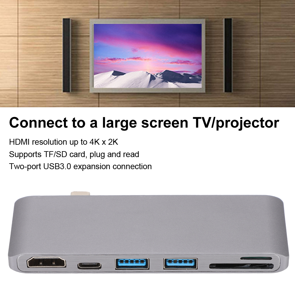 Silberner Hub mit Anschlüssen unter einem Fernsehbildschirm mit einer Berglandschaft. Text: Verbinden Sie sich mit einem Großbildfernseher/Projektor, HDMI-Auflösung bis zu 4K.