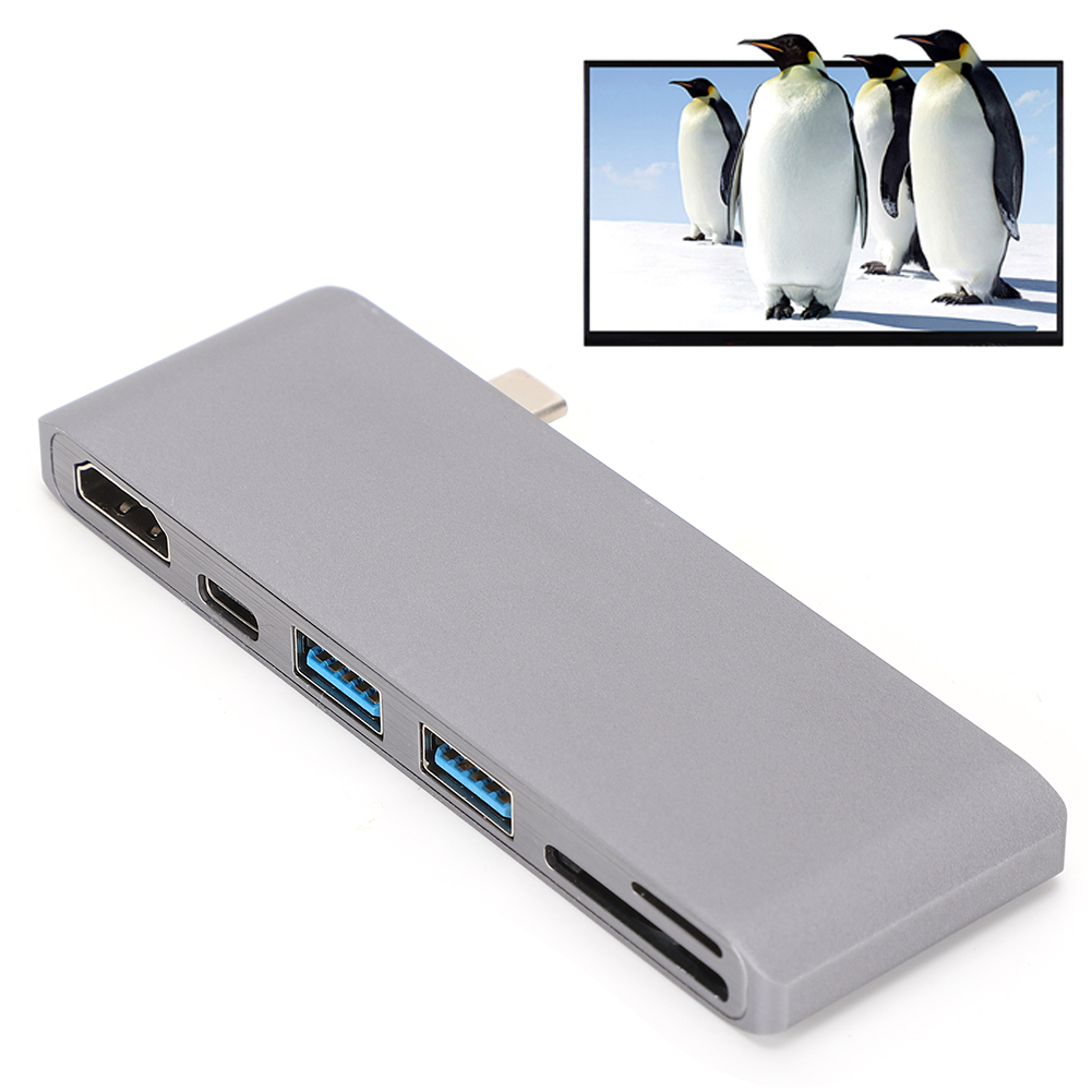 Grauer USB-Hub mit verschiedenen Anschlüssen. Ein Bildschirm zeigt Pinguine im Schnee. Weißer Hintergrund.