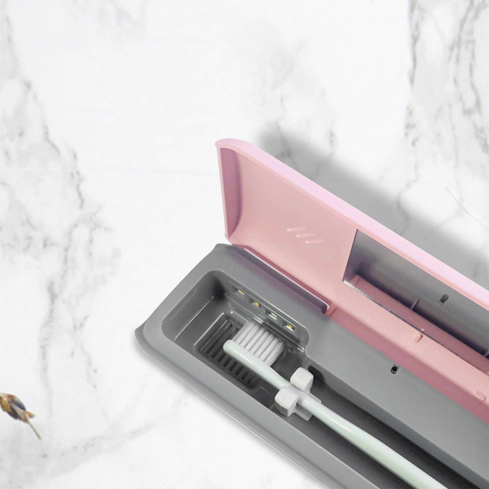Geöffnete rosa Zahnbürstenetui mit grauem Innenraum, in dem eine weiße Zahnbürste liegt. Das Etui liegt auf einer marmorähnlichen Oberfläche.