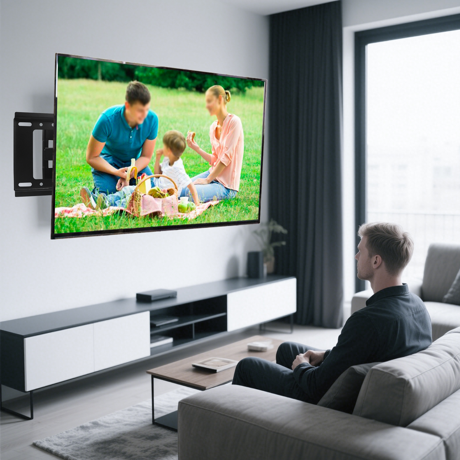 Ein Mann sieht fern, auf dem ein Familienpicknick zu sehen ist. Der Fernseher ist an der Wand montiert. Vor dem Fernseher befindet sich ein Sofa.