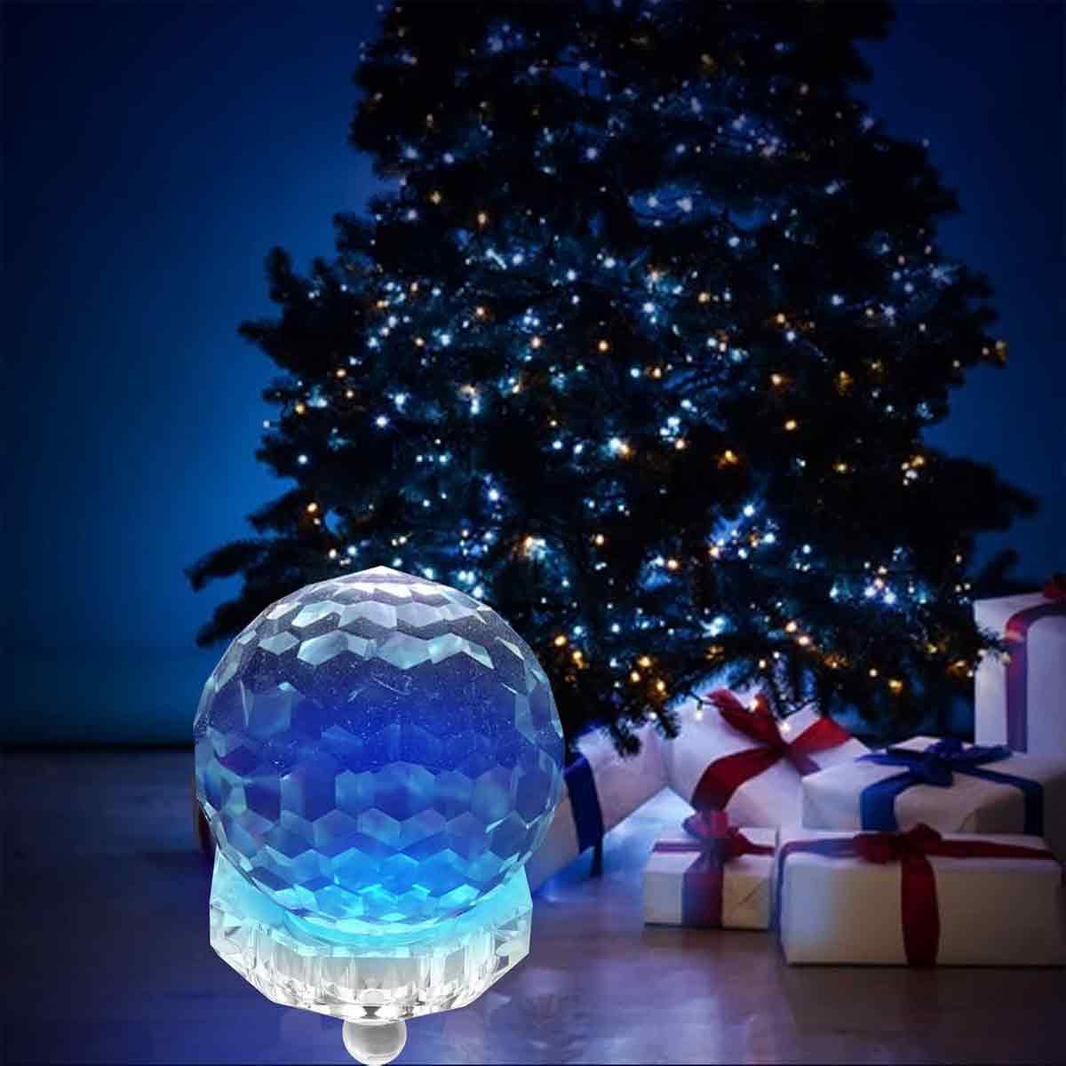 Ein Kristallkugel auf einem Ständer, ein Weihnachtsbaum mit Lichtern im Hintergrund und Geschenke unter dem Baum. Die Szene ist festlich.