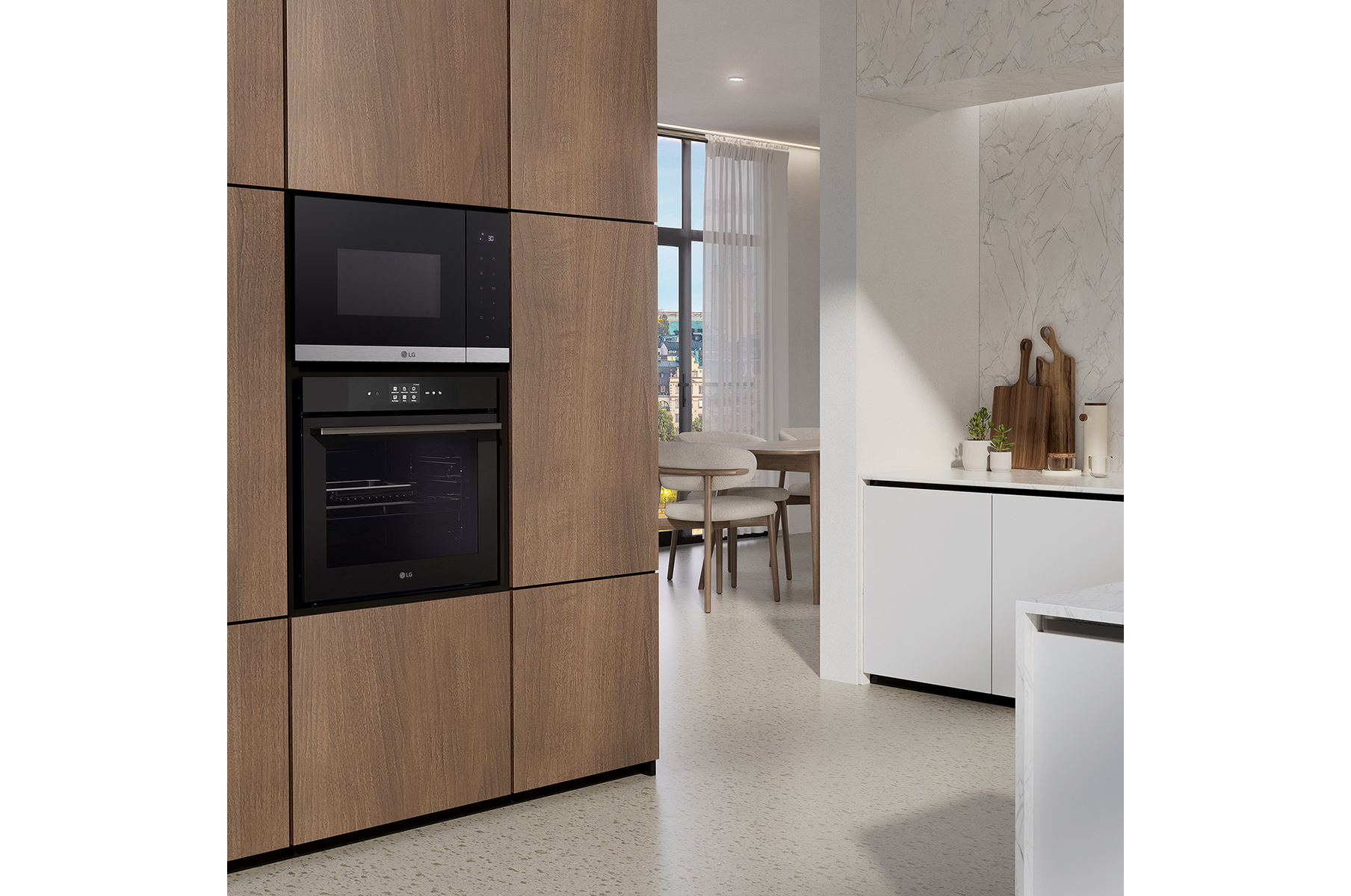 Una cocina moderna con horno y microondas negros empotrados. Armarios de madera enmarcan los electrodomésticos. Se ve un comedor al fondo.
