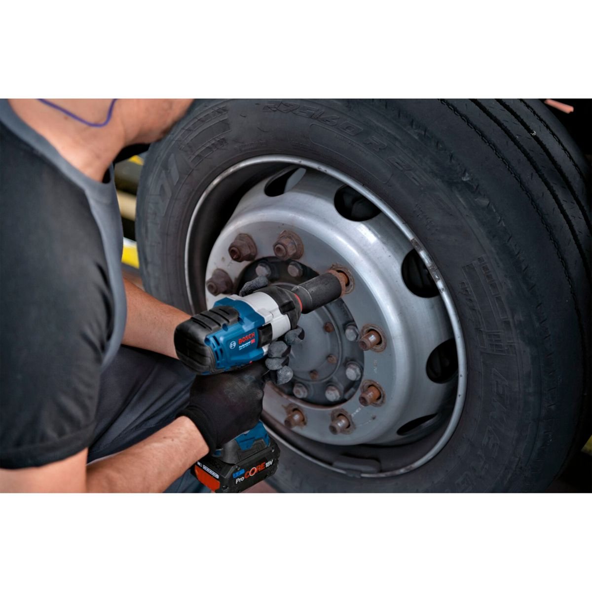 Una persona usa una llave de impacto Bosch para quitar una tuerca de rueda de un camión. La escena es en un taller.