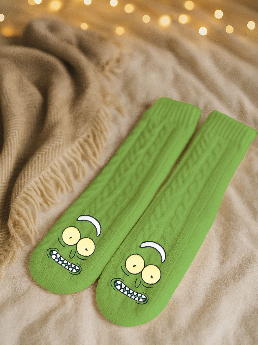 Zwei grüne Socken mit Cartoon-Gesichtern liegen auf einem Bett. Eine beige Decke und Lichterketten sind im Hintergrund.