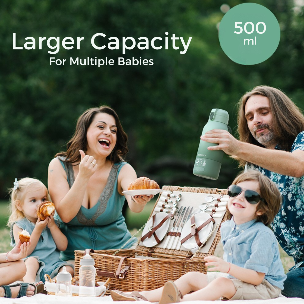 Family picnic. A mother holds a croissant, a man holds a bottle, and children eat. Picnic basket in front.