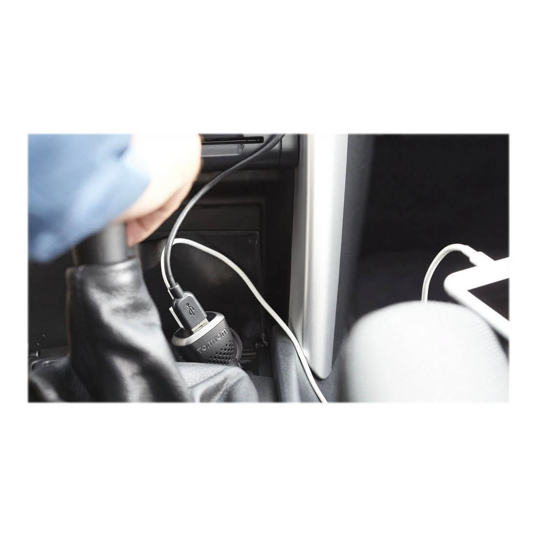 Una persona collega un caricatore USB alla presa di corrente dell'auto. Un telefono si ricarica con un cavo bianco.