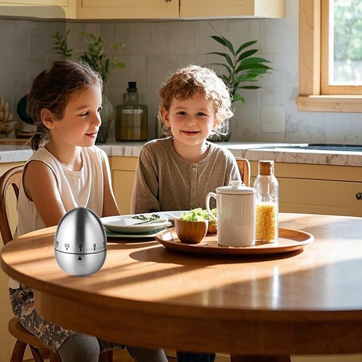 Zwei Kinder an einem Tisch mit einem Timer. Ein Holztablett hält eine Tasse, Gemüse und eine Flasche. Küchenschränke sind im Hintergrund.