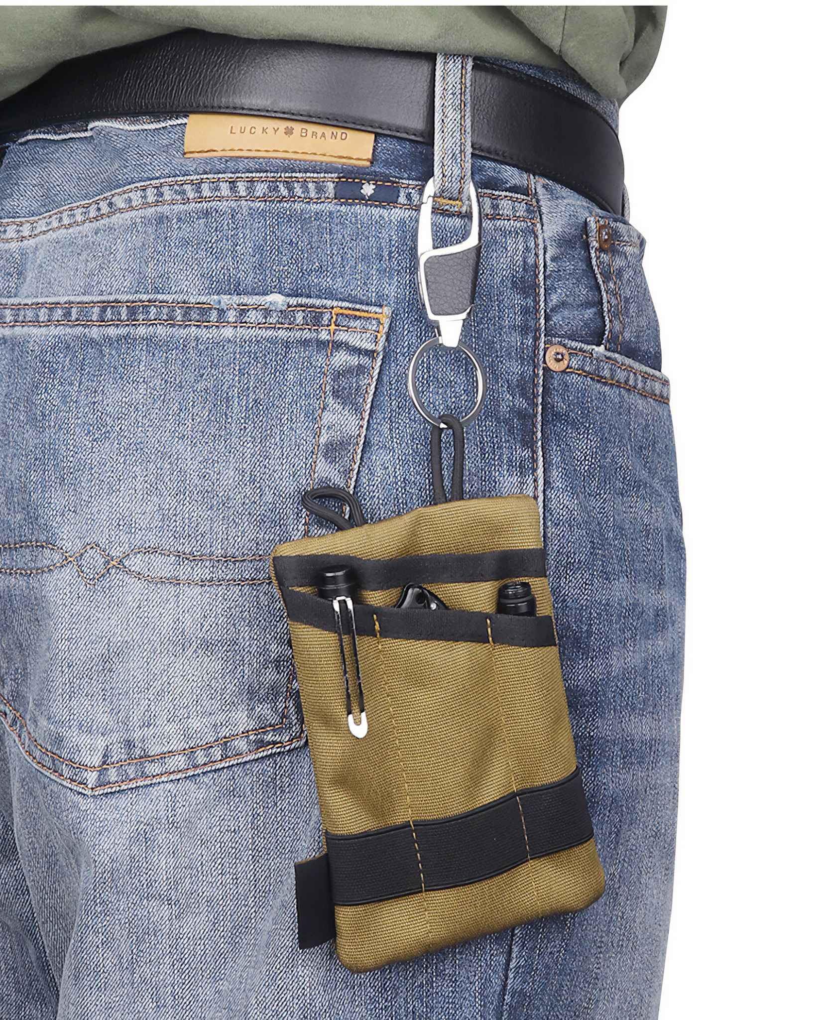 Eine Person, die blaue Jeans mit einem schwarzen Gürtel trägt. Am Gürtel ist ein kleines Täschchen mit Gegenständen befestigt.