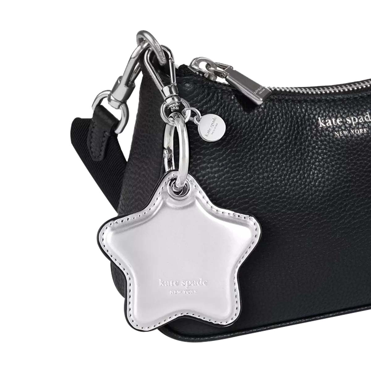 Nahaufnahme einer schwarzen Kate Spade Ledertasche mit silberner Hardware und einem sternförmigen Schlüsselanhänger.