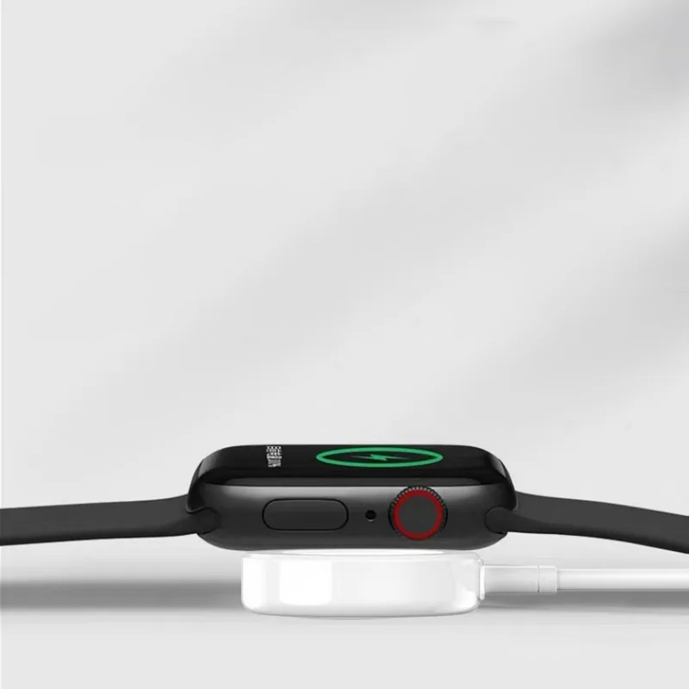 Schwarze Smartwatch auf weißer Ladestation. Uhr zeigt Ladesymbol. Roter Knopf an der Seite. Weißer Hintergrund.