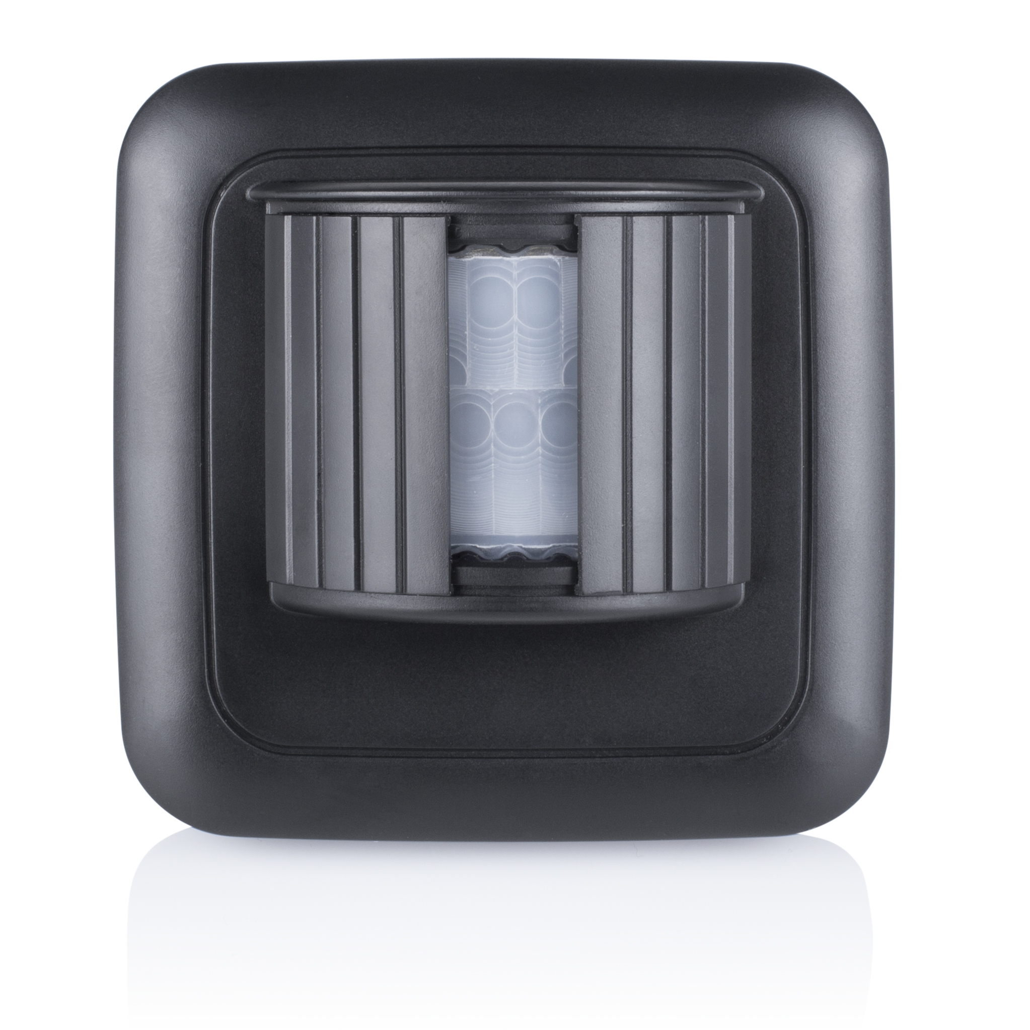 Czujnik ruchu w kolorze czarnym, prostokątny z zaokrąglonymi krawędziami, zamontowany na białej powierzchni z odbiciem.