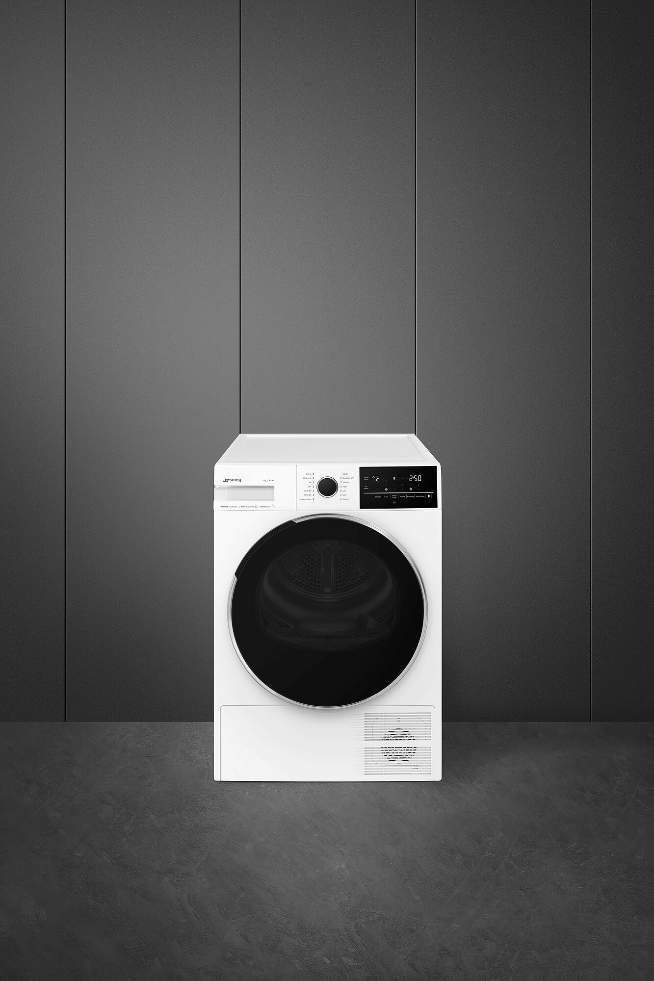 Una secadora Smeg blanca sobre un suelo gris contra una pared gris. Tiene una puerta negra y una pantalla digital.