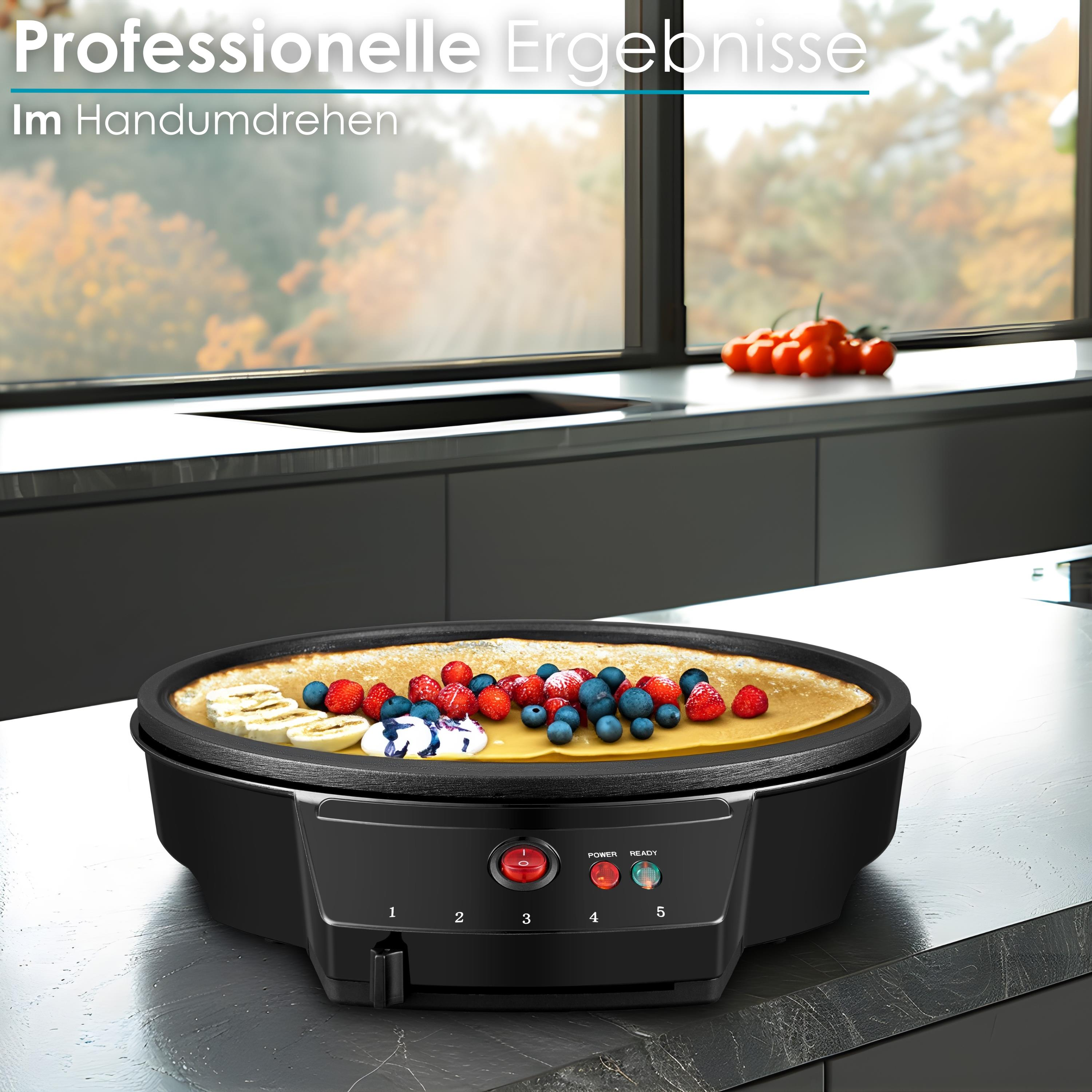 Schwarzer Crêpes-Maker mit Crêpe, belegt mit Beeren und Bananen. Tomaten liegen im Hintergrund auf der Theke.
