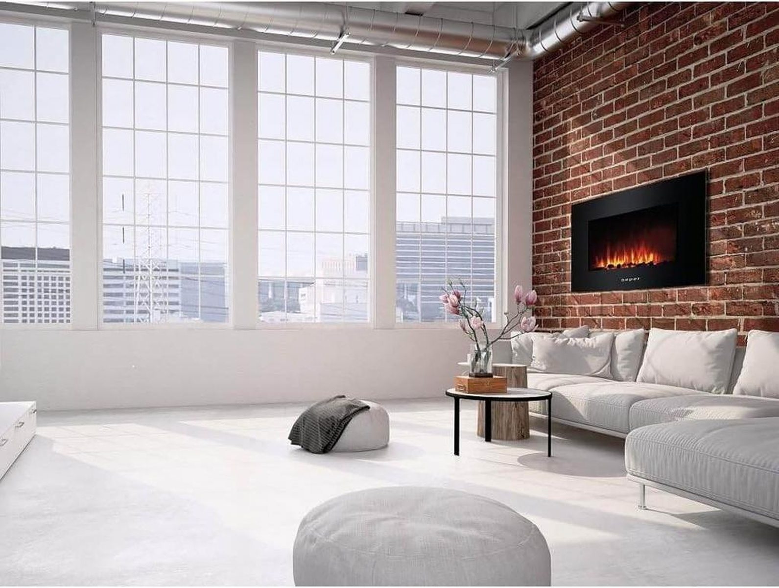 Modernes Wohnzimmer mit großen Fenstern, Backsteinmauer und Kamin. Enthält ein Sofa, einen Couchtisch und Sitzsäcke.