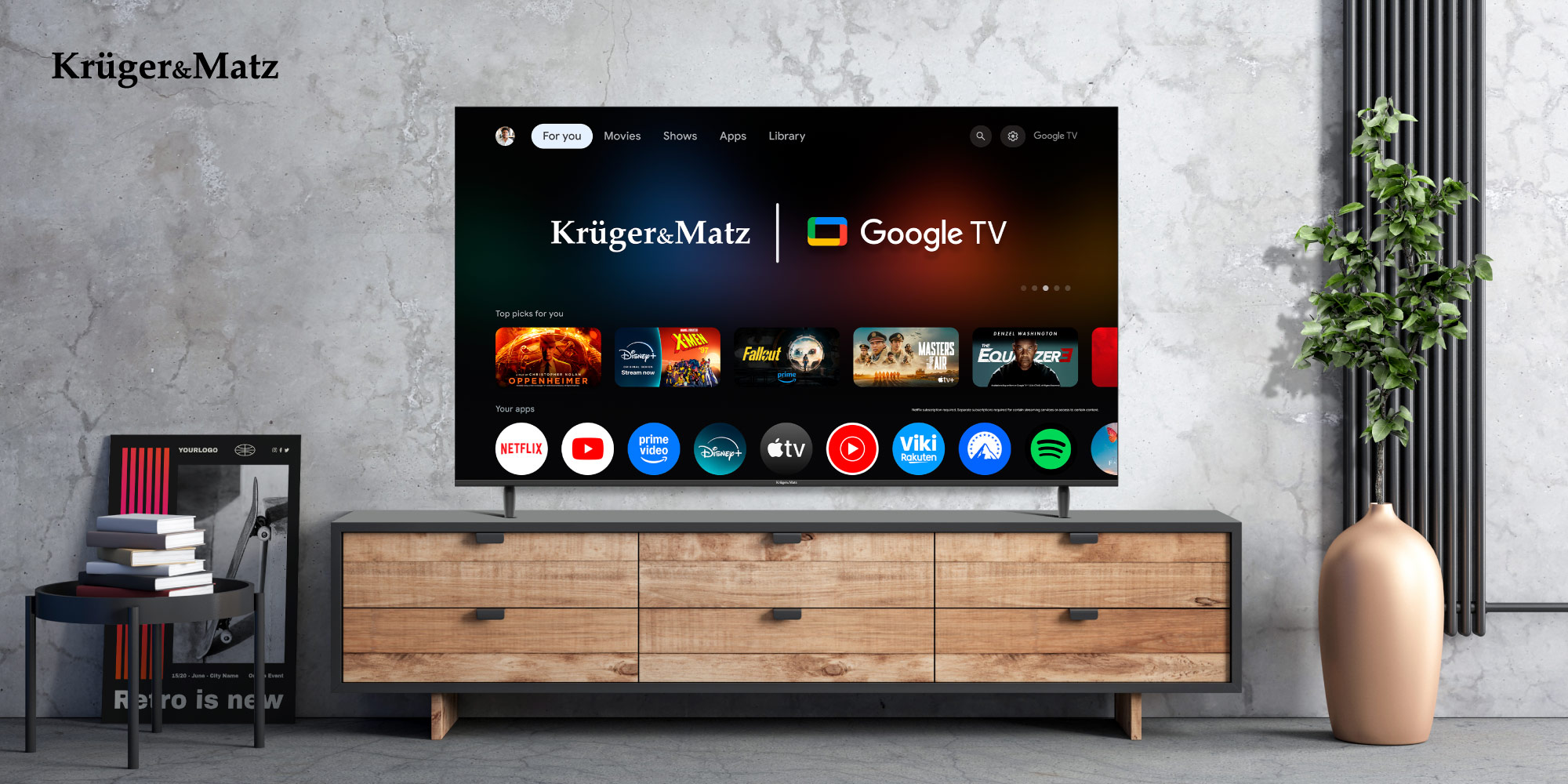 Telewizor wyświetla interfejs Google TV, pokazując aplikacje. Stoi na drewnianej szafce w pokoju z rośliną w beżowym wazonie.