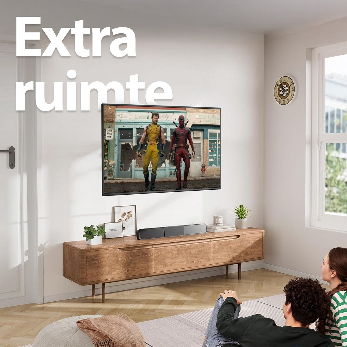 A living room with a TV showing Wolverine and Deadpool. A soundbar, wooden cabinet, and a couple watching. Text 'Extra ruimte'.