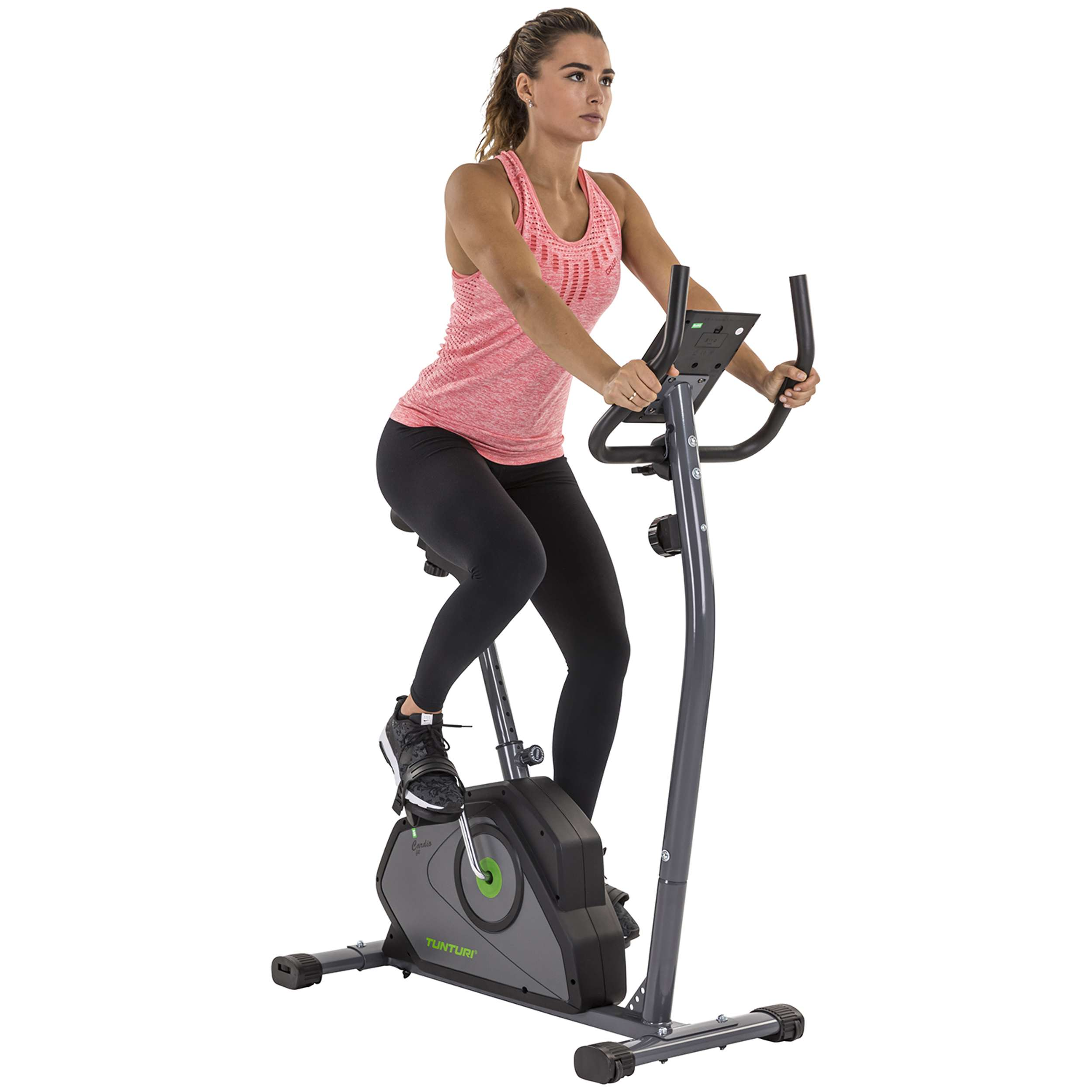 Een vrouw op een hometrainer. Ze draagt een roze top en een zwarte legging. De fiets is grijs en zwart.