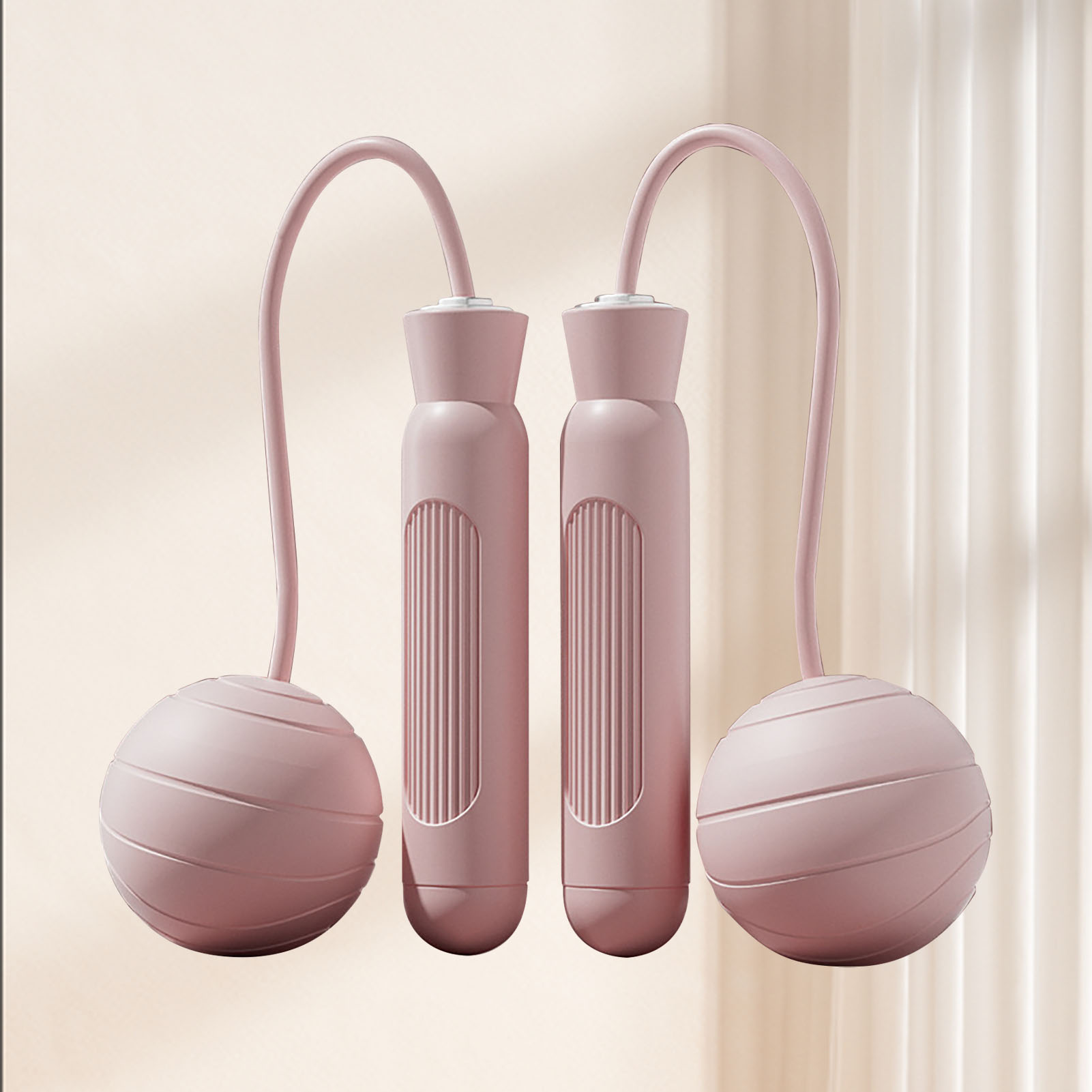 Ein rosa Springseil mit zwei Griffen und zwei beschwerten Kugeln. Der Hintergrund ist hellbeige.