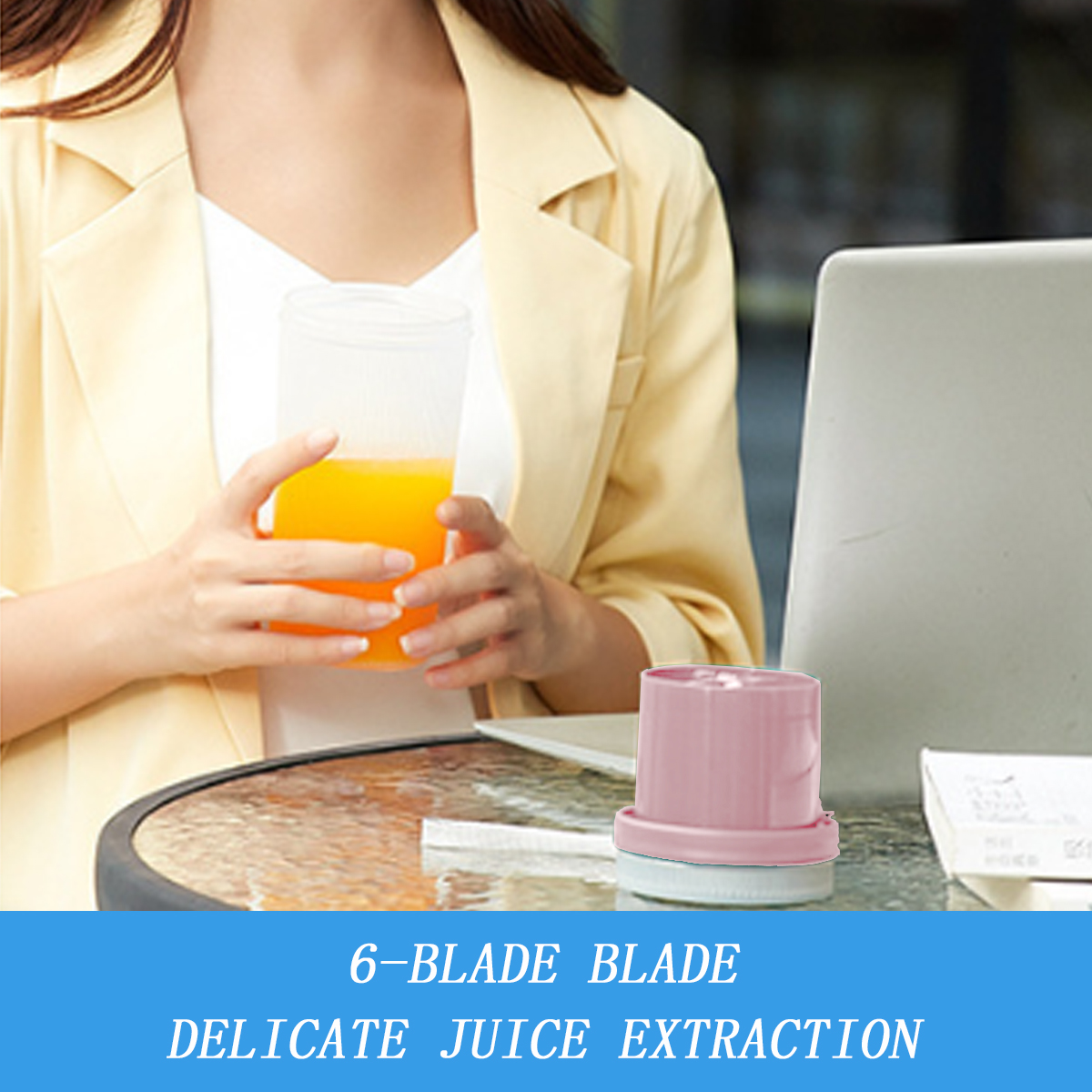 Eine Person hält ein Glas mit Orangensaft. Ein rosa Blenderteil steht auf einem Tisch mit Laptop und Papier.