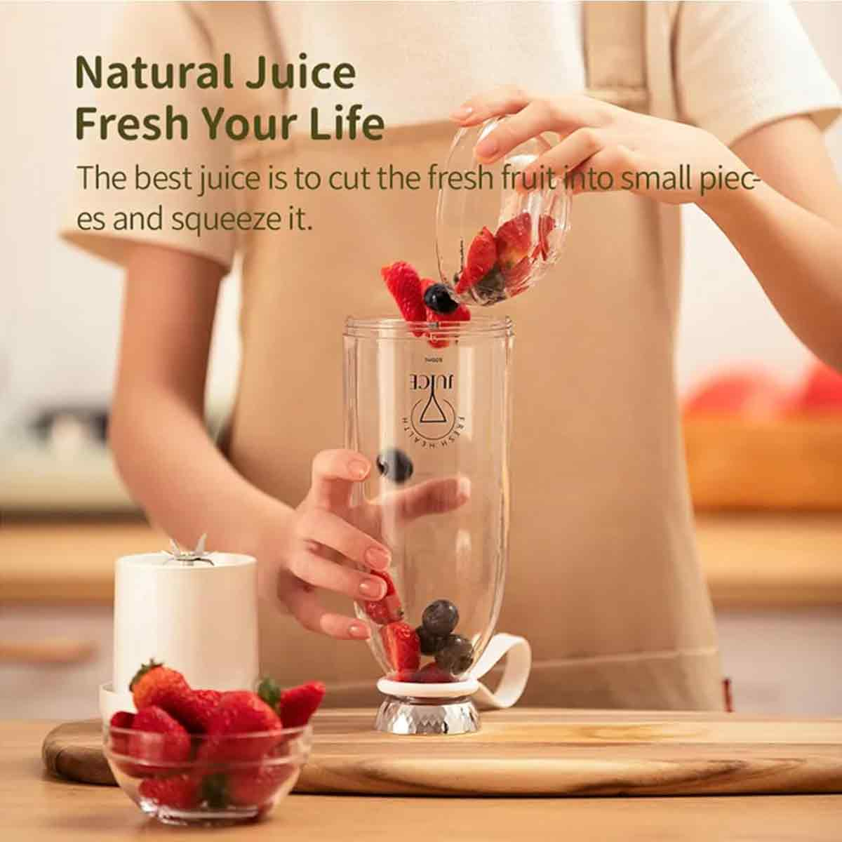 Person gießt Früchte in einen Entsafter. Erdbeeren und Blaubeeren sind sichtbar. Text: Natürlicher Saft, Frische dein Leben, Bester Saft ist frisches Obst.