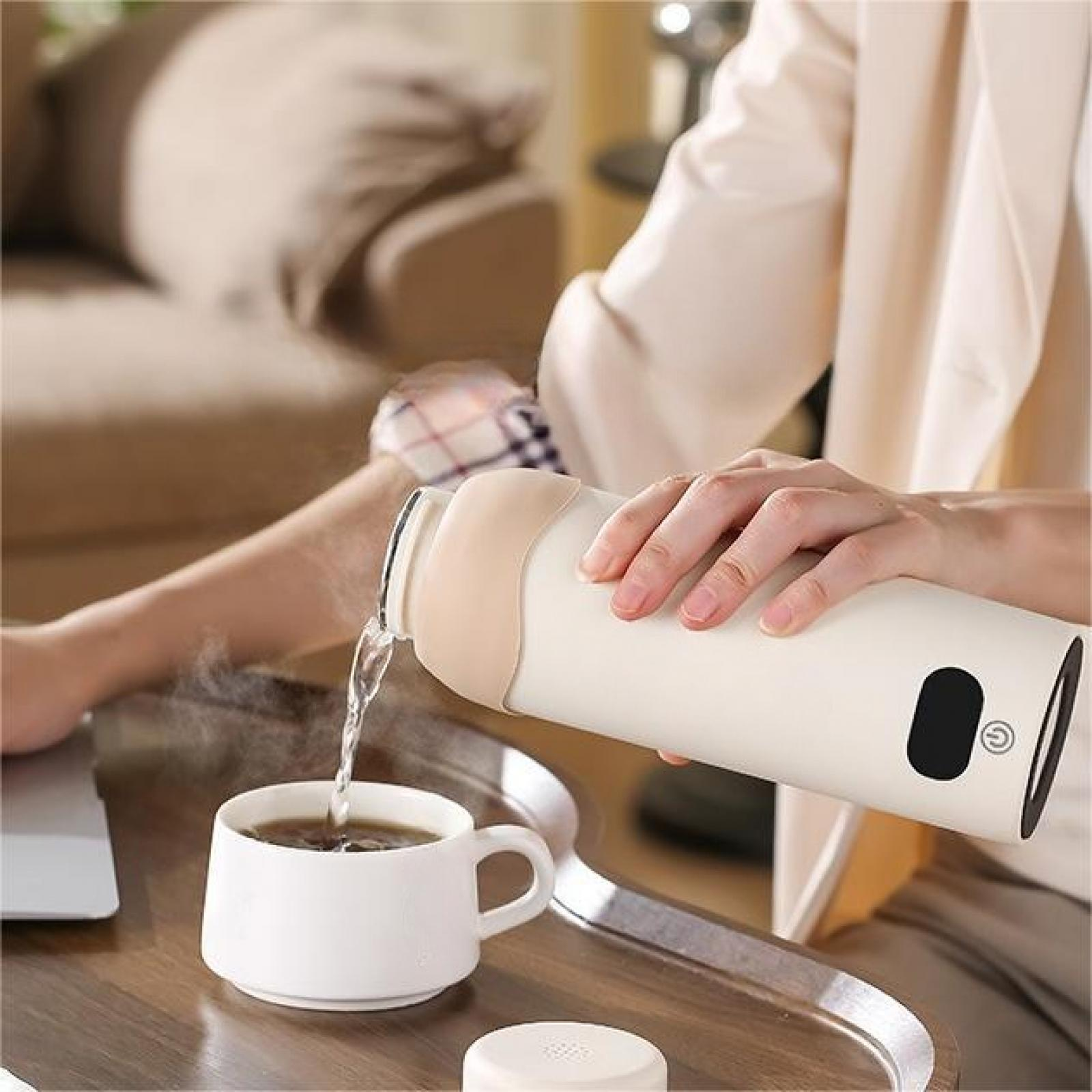 Eine Person gießt heißes Wasser aus einer weißen Thermoskanne in eine weiße Tasse. Ein Laptop ist links sichtbar.