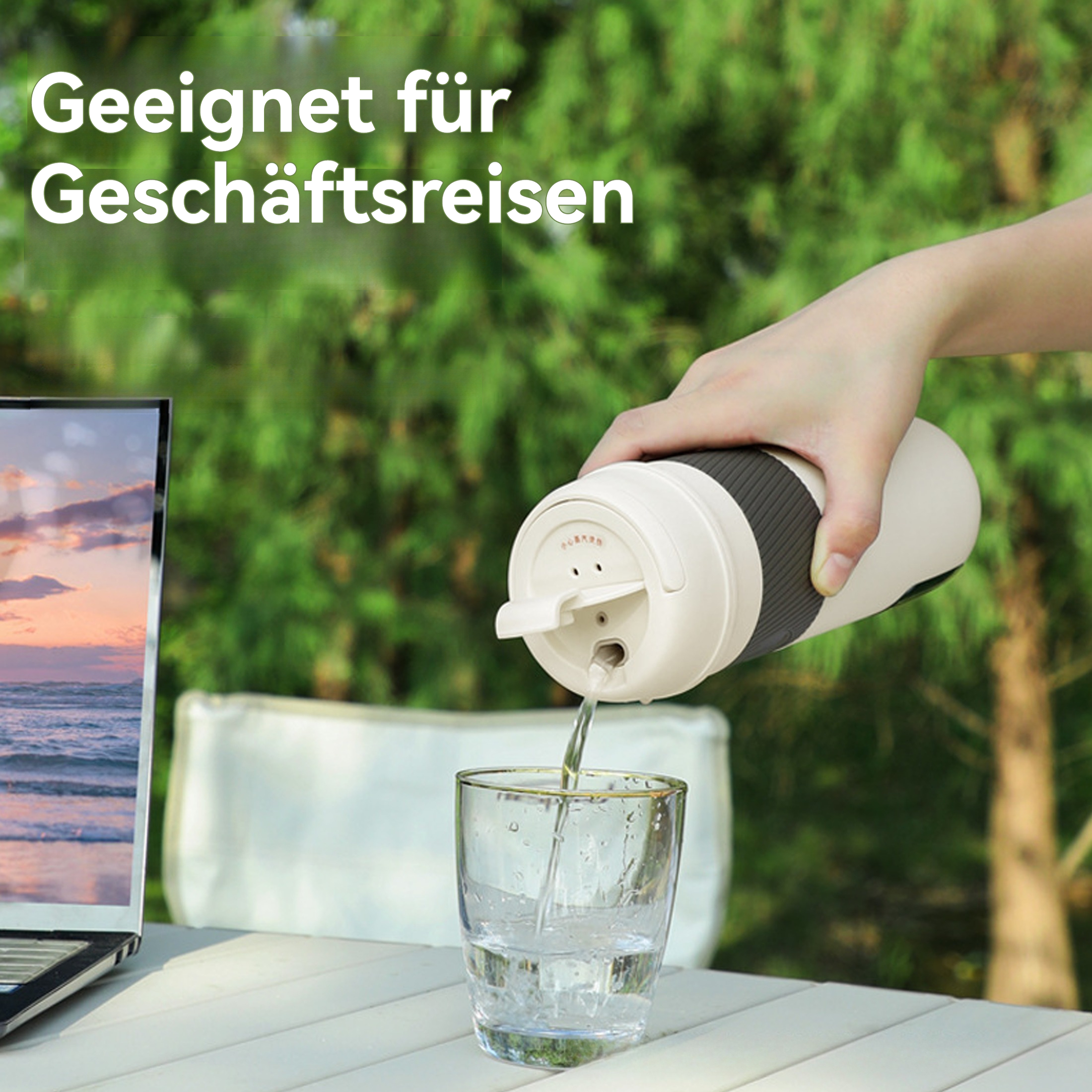Eine Person gießt Wasser aus einem Reisebecher in ein Glas. Ein Laptop steht daneben auf einem weißen Tisch, mit einem verschwommenen grünen Hintergrund.