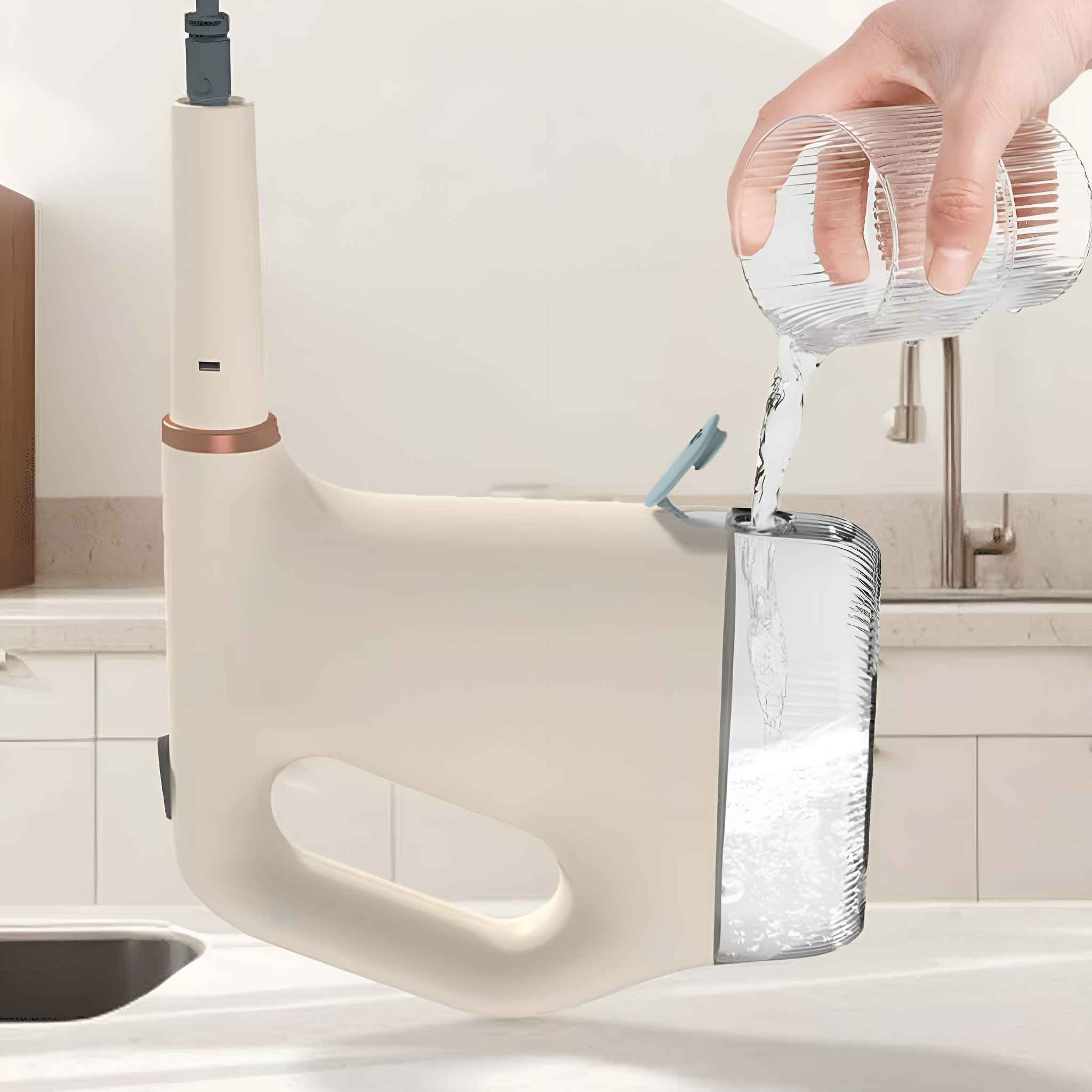 Eine Hand gießt Wasser aus einem Glas in ein helles Gerät. Die Szene spielt in einer Küche.