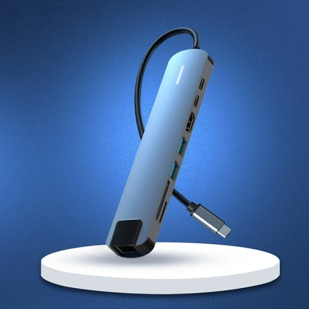 Ein blauer USB-C-Hub steht auf einem weißen Ständer vor einem blauen Hintergrund. Es hat mehrere Anschlüsse und ein schwarzes Kabel.
