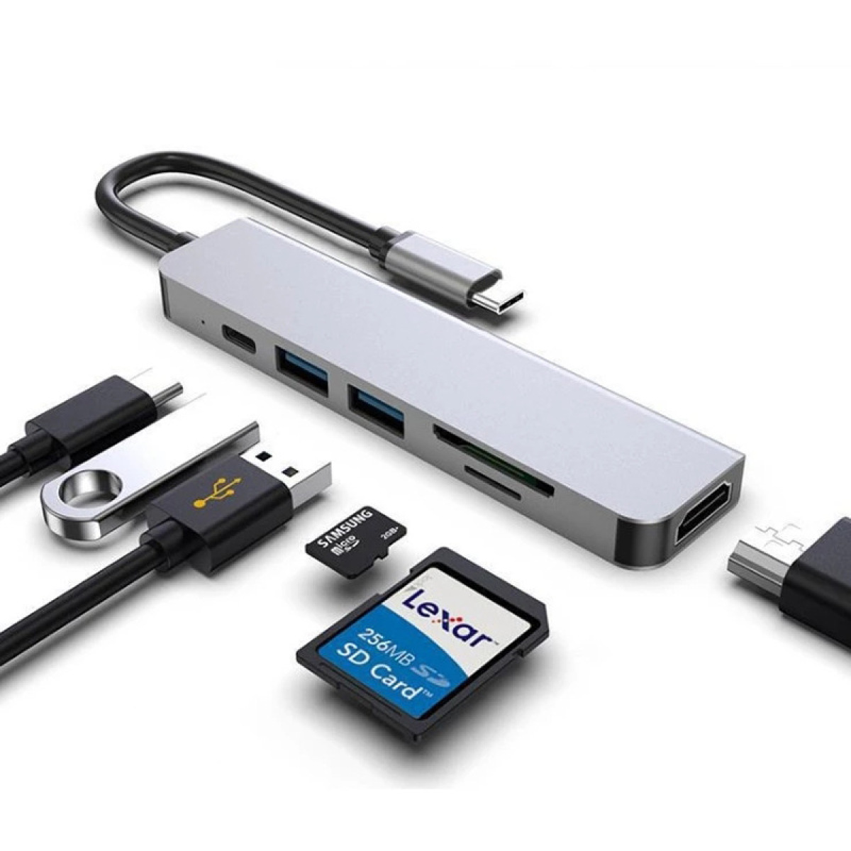 Ein silberner USB-Hub mit mehreren Anschlüssen, USB-Sticks, SD-Karten und verschiedene Kabel liegen auf weißem Grund.