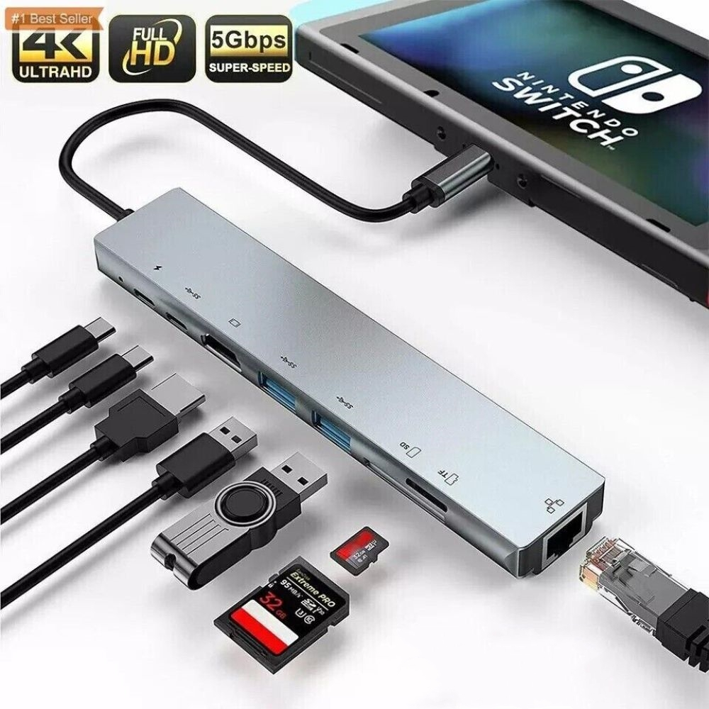 Ein silberner Nintendo Switch-Hub mit mehreren Anschlüssen und angeschlossenem Zubehör. Im Hintergrund befindet sich eine Nintendo Switch.
