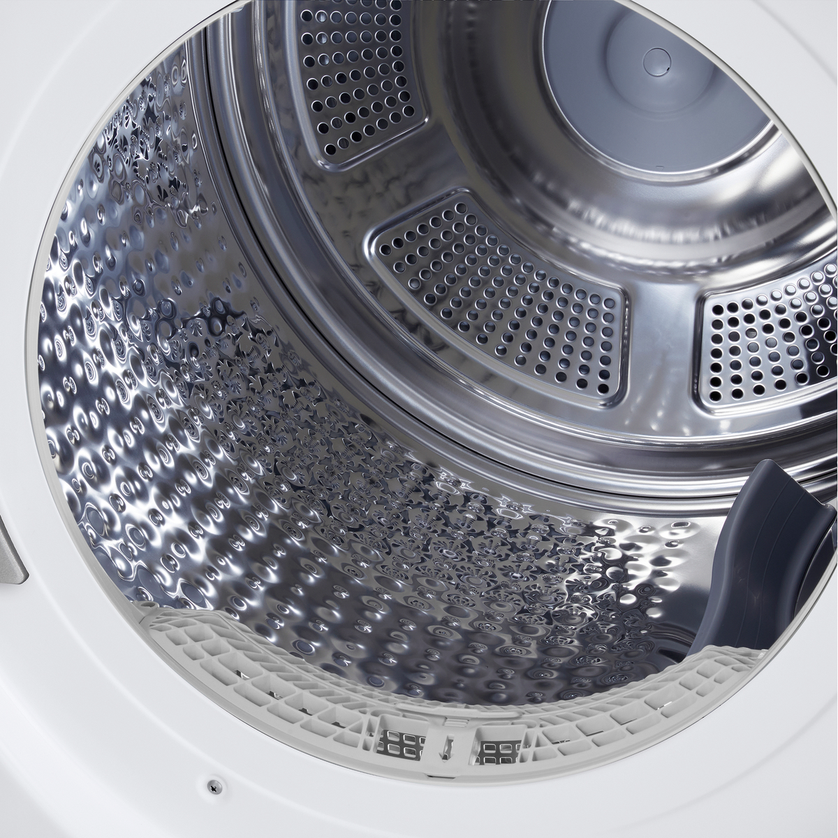 Inside a washing machine drum. The stainless steel interior has perforations and a textured surface. A white plastic rim is at the bottom.