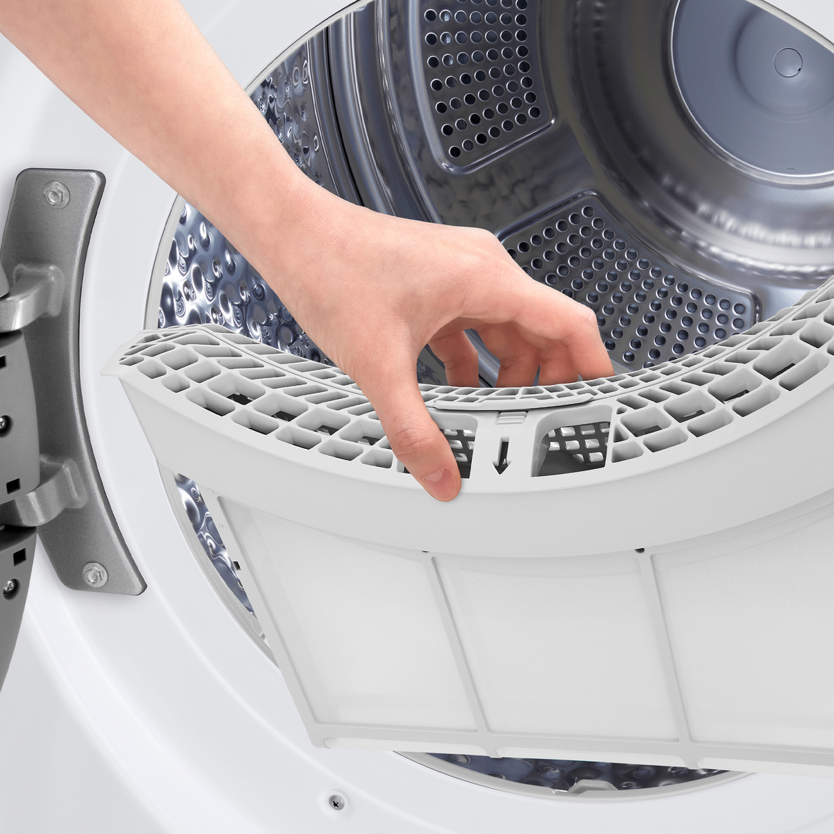 A hand pulls out a white lint filter from a washing machine. The machine is white and has a silver interior.