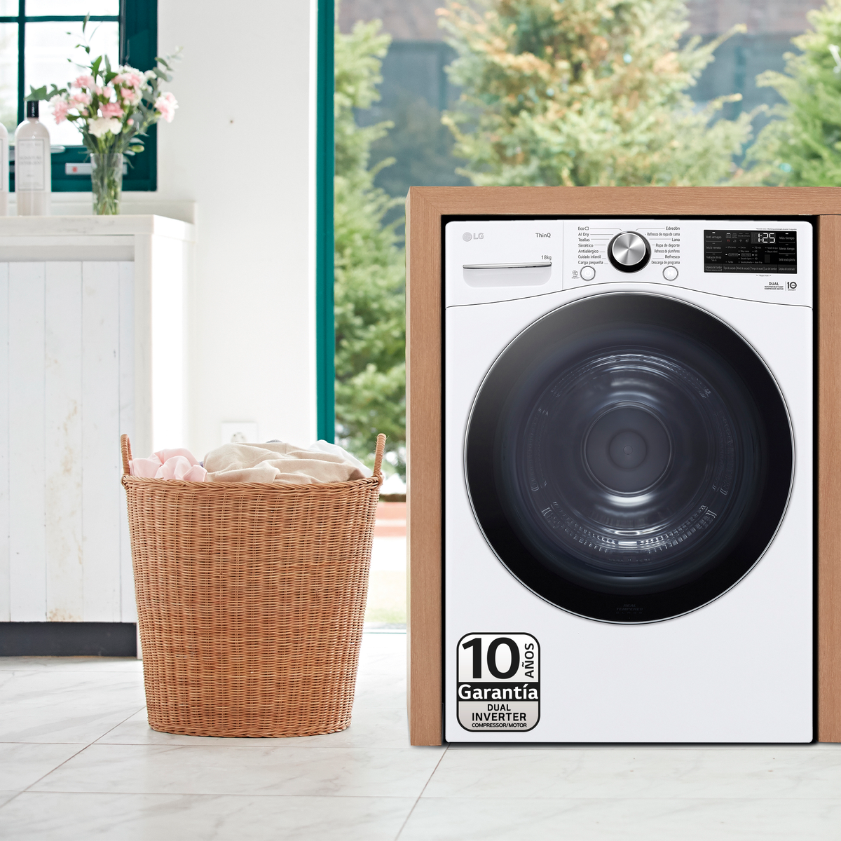 A white LG washing machine stands next to a wicker laundry basket. A window and flowers are in the background.