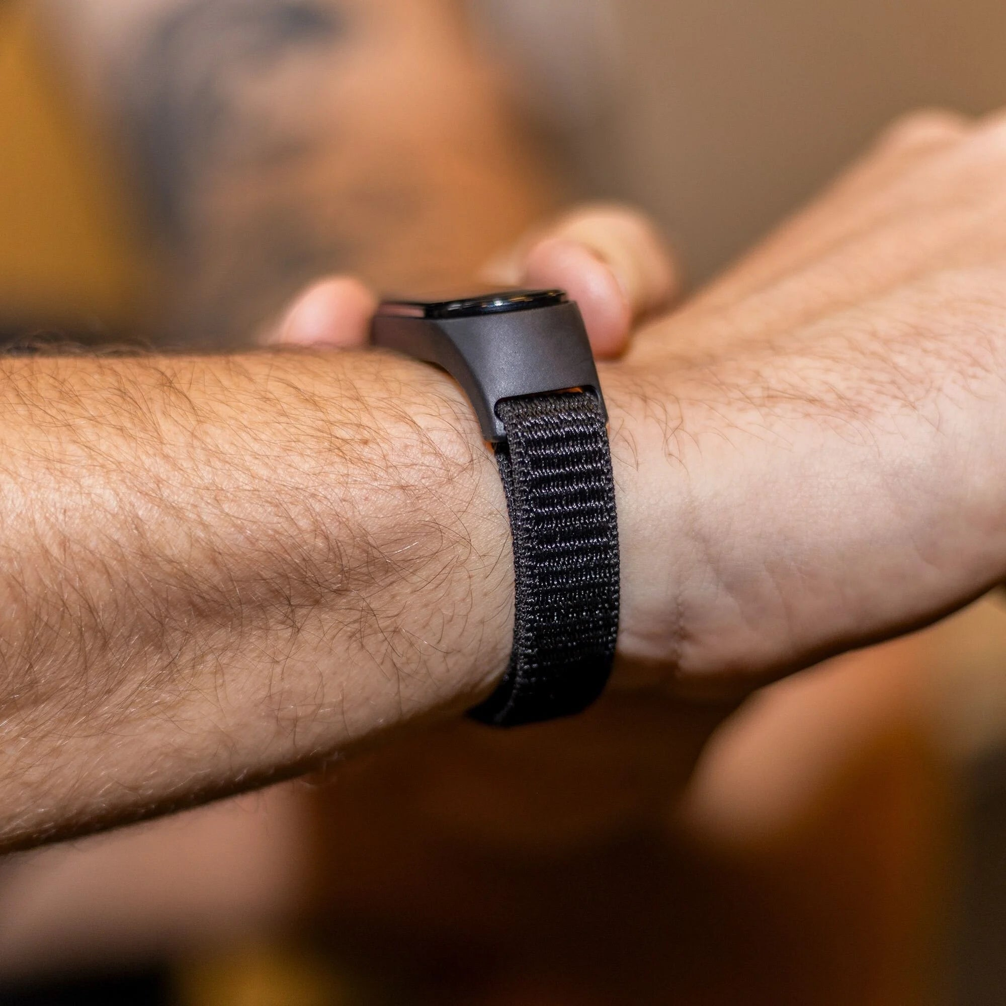 Das Handgelenk einer Person mit einer schwarzen Uhr. Die Uhr hat ein schwarzes Armband. Die Haut ist sichtbar und behaart.